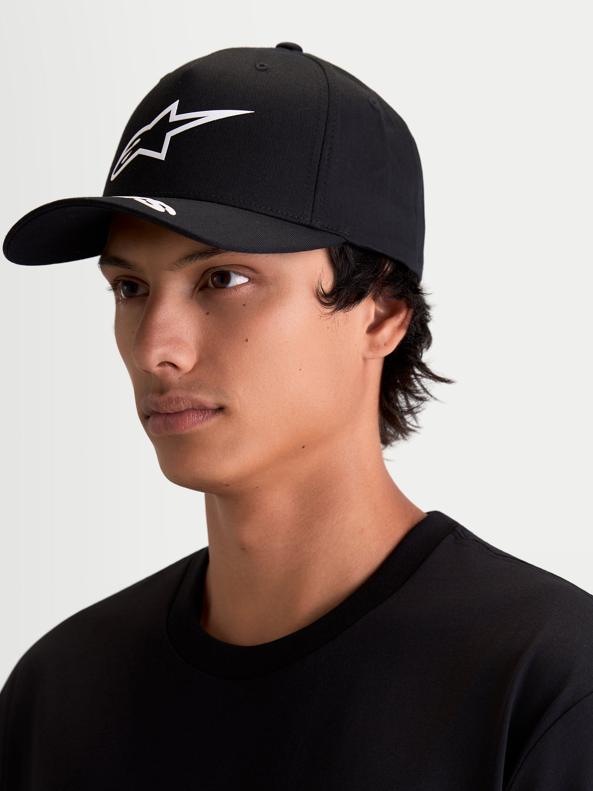 Alpinestars Arclight Hat, czapka z daszkiem, odzież sportowa dla mężczyzn i kobiet, czarna, białe teksturowane logo Astars puff-print, zakrzywiony daszek, usztywniona korona, pokazana na modelu