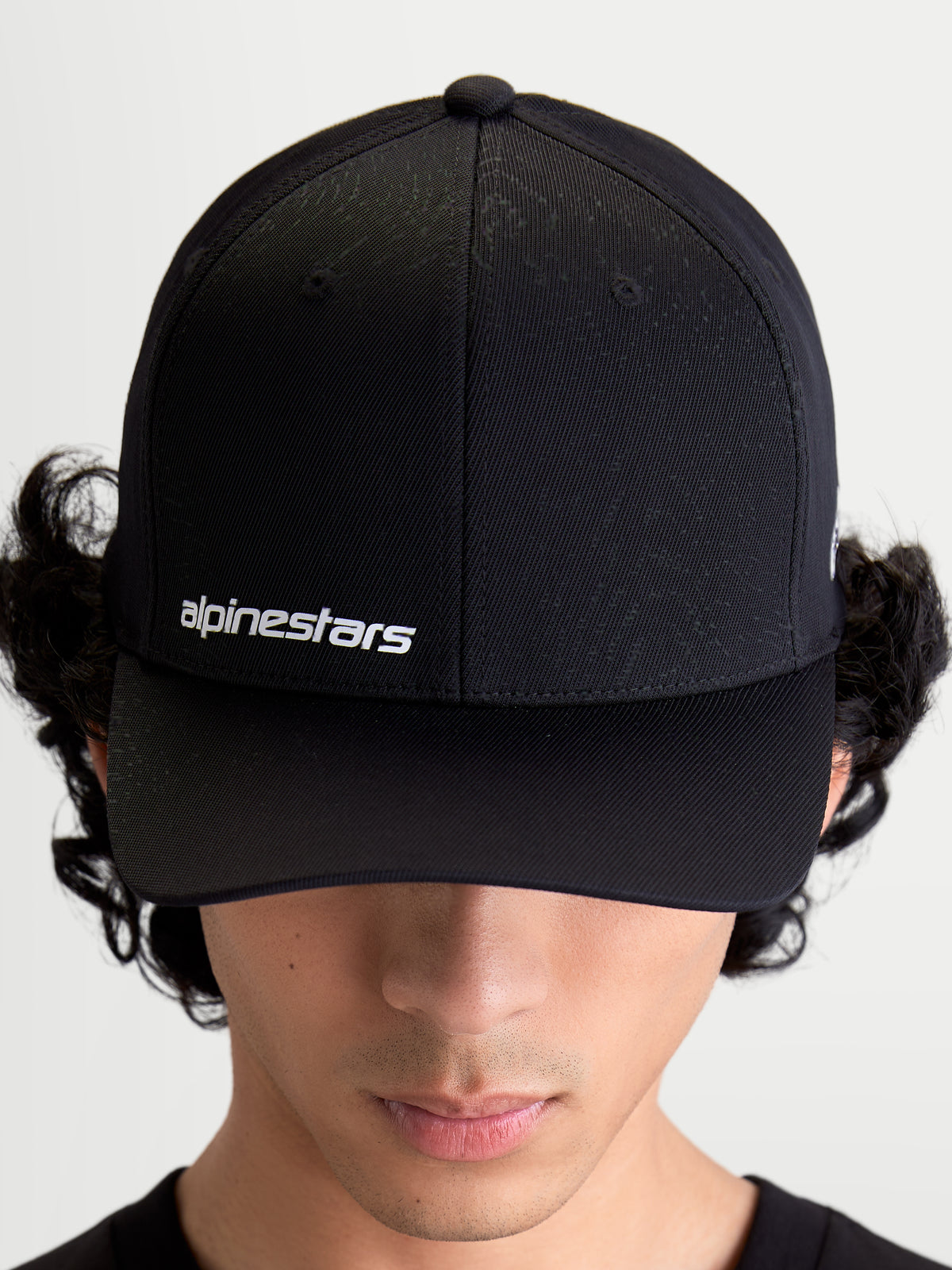 Alpinestars Points Hat, czarna czapka z daszkiem typu sportswear na modelu, białe logo słowne Alpinestars z przodu, lekka konstrukcja z nylonu tactel.
