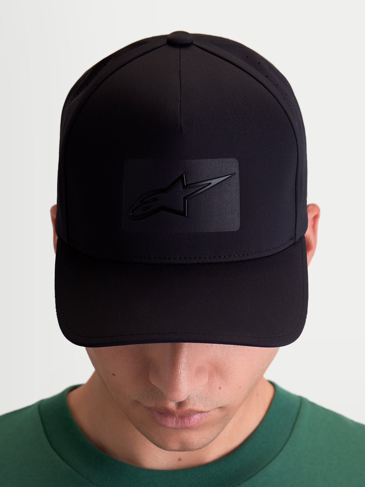 Alpinestars Algo Perf Adjustable Hat, czarna czapka z daszkiem, odzież sportowa unisex, tkanina techniczna z boczną perforacją, zakrzywiony daszek i usztywniona korona, widok z przodu na modelu z logo Astars sonic-weld.