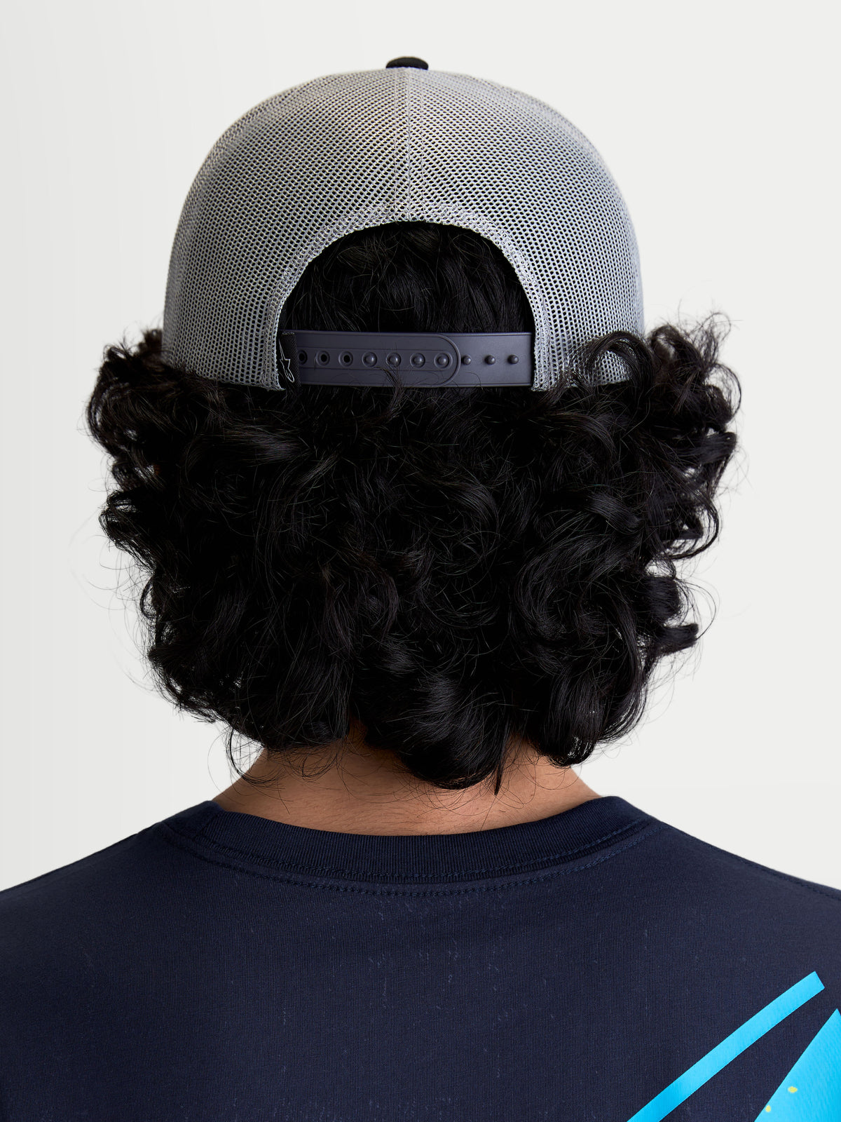 Alpinestars Czapka Z Daszkiem Gravel, szara i czarna czapka typu trucker, widok z tyłu na modelu prezentujący oddychający tył z siatki oraz regulowane zapięcie snapback zapewniające indywidualne dopasowanie.