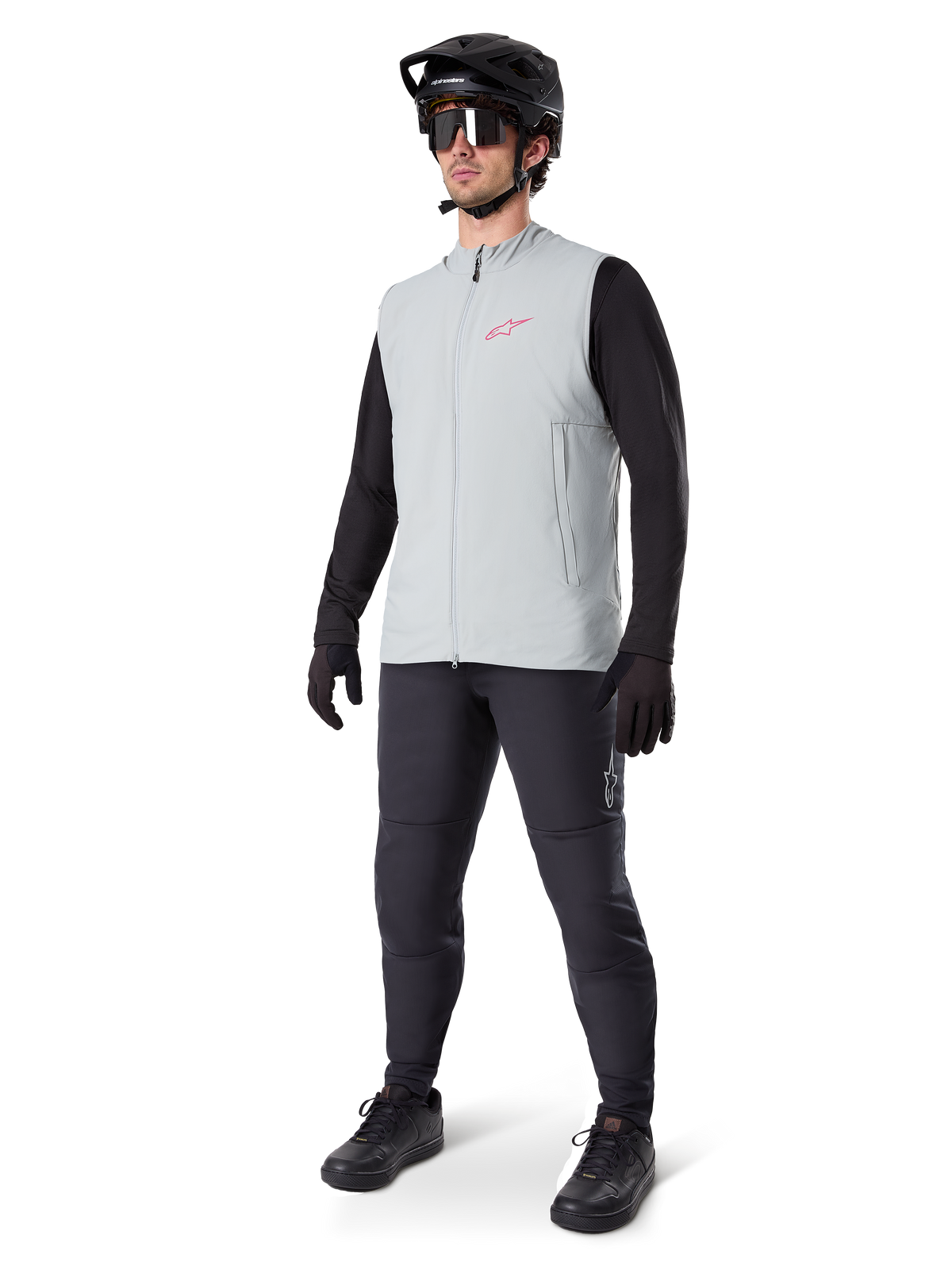 Alpinestars A-Dura Thermal Vest, szara tytanowa kamizelka rowerowa z różowym logo, noszona przez modela w czarnej koszulce z długim rękawem, ciemnoszarych spodniach i czarnym kasku MTB, profesjonalna odzież do jazdy w niskich temperaturach
