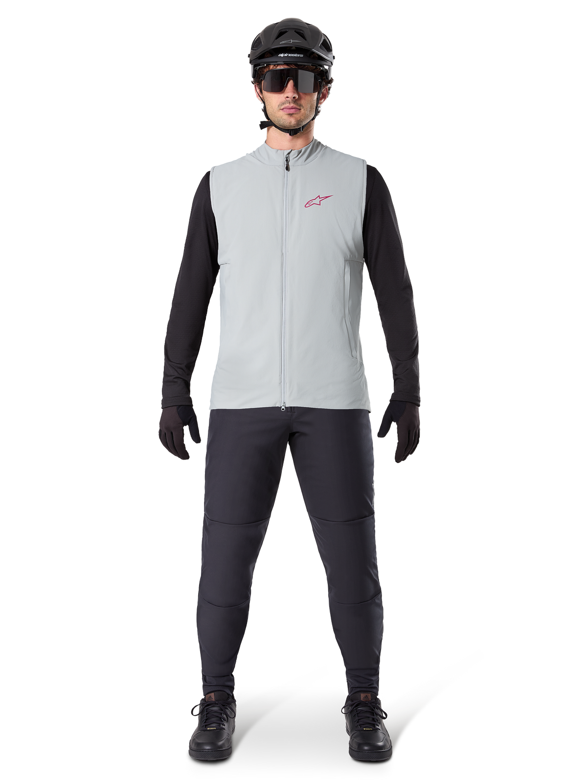 Kamizelka termiczna Alpinestars A-Dura, kamizelka rowerowa, szary Titanium, zestawiona z czarną koszulką z długim rękawem i czarnymi spodniami, czarny kask i okulary przeciwsłoneczne, czerwone logo Alpinestars, lekka izolacja termiczna do jazdy na rowerze górskim