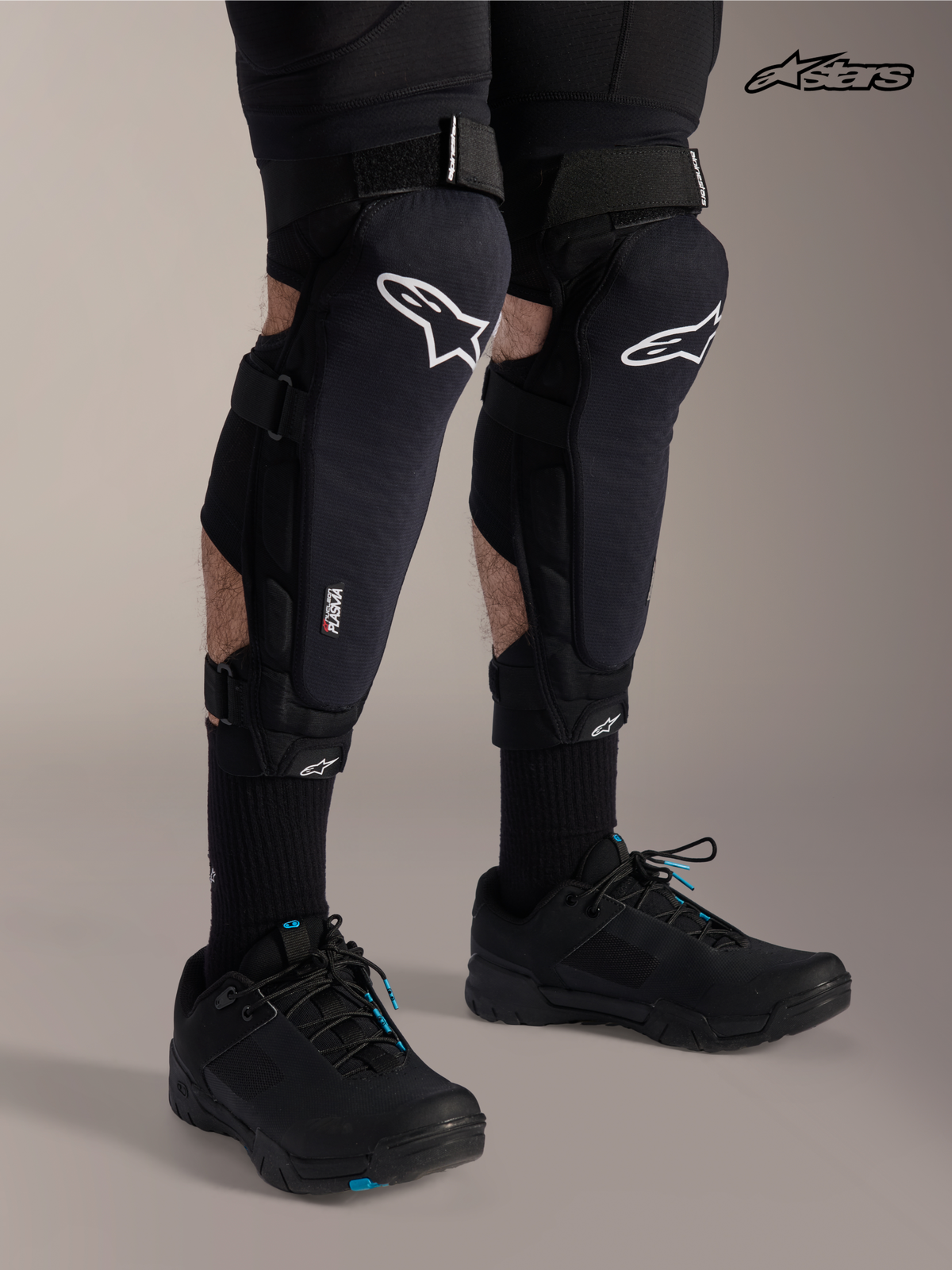 Alpinestars Ochraniacz Kolano / Piszczel A-Impact Plasma Pro, czarne ochraniacze na kolana i golenie MTB z białym logo, na modelu prezentującym potrójne zapięcie na paski i ochronę Nucleon Plasma