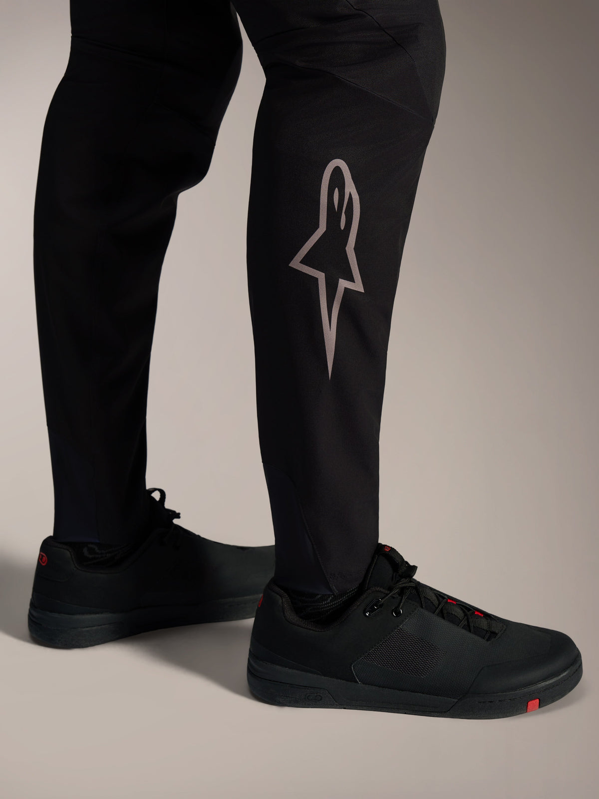 Czarne spodnie MTB A-Supra Elite ze srebrnym logo Astars na dole nogawki, zaprojektowane do wyczynowej jazdy górskiej.