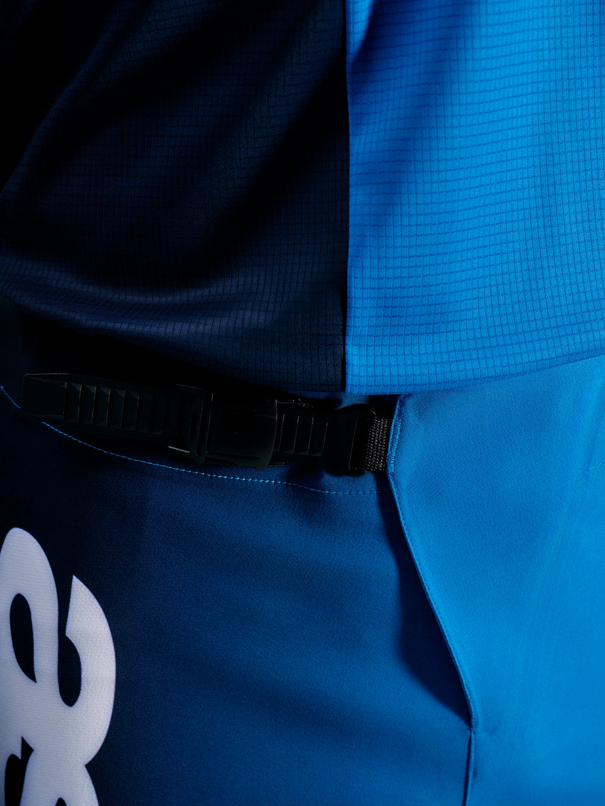Spodnie A-Supra Elite Faded Bright Blue z czarnym zapięciem zapadkowym zapewniającym bezpieczne dopasowanie na szlaku.