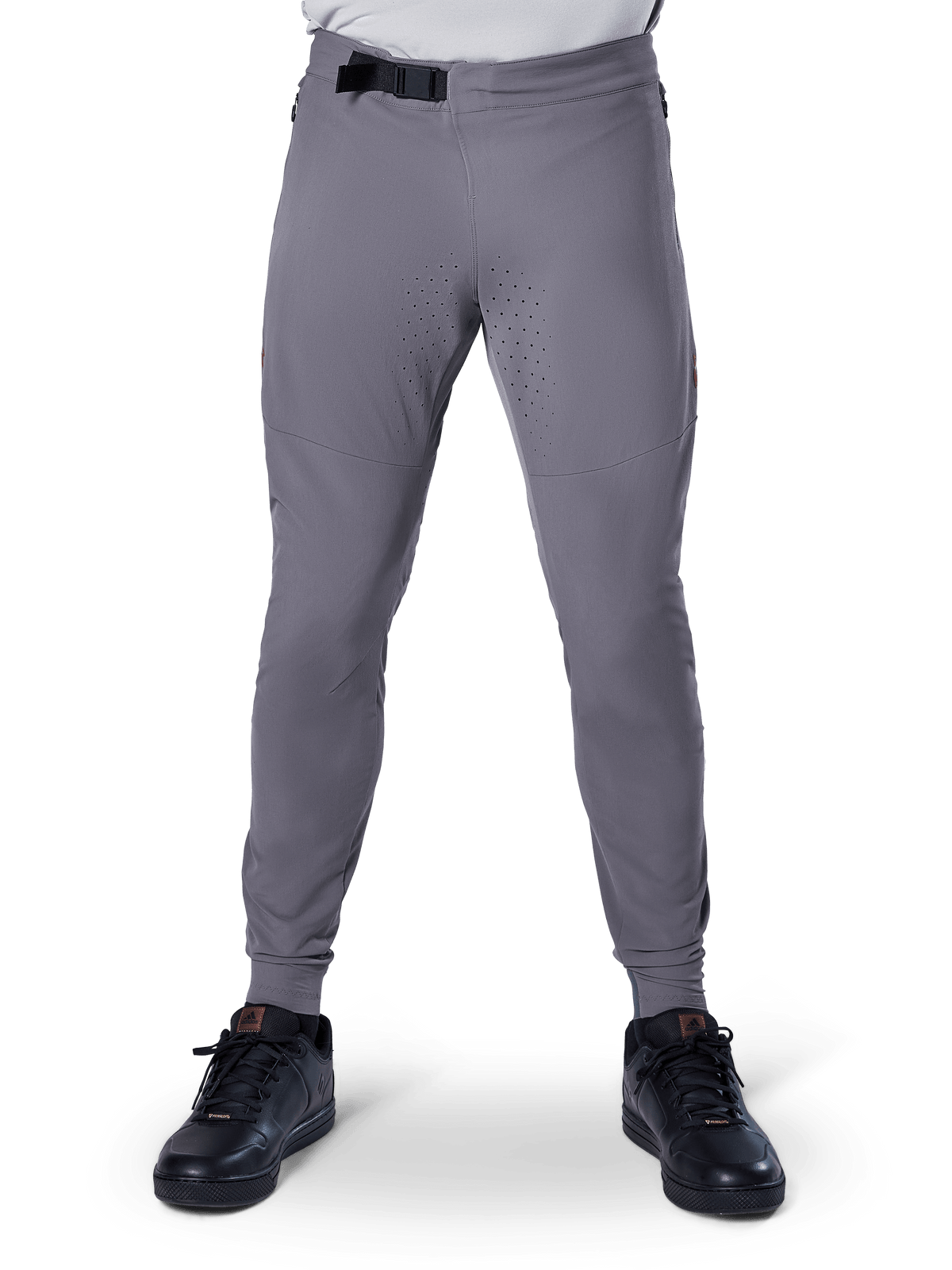 Spodnie Alpinestars A-Aria Elite, spodnie rowerowe MTB, ciemnoszare, z laserowymi perforacjami na wewnętrznej stronie ud dla wentylacji i magnetycznym zapięciem w pasie, sportowy krój ze zwężanymi nogawkami, noszone z czarnymi butami sportowymi