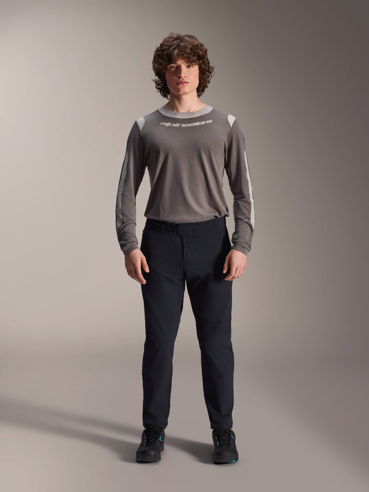 Alpinestars A-Dura Elite Pants, Black Mountain Bike Pants, technical cycling apparel with a regular fit, worn with a gray long-sleeved jersey and black shoes, durable Cordura® construction for off-road riding