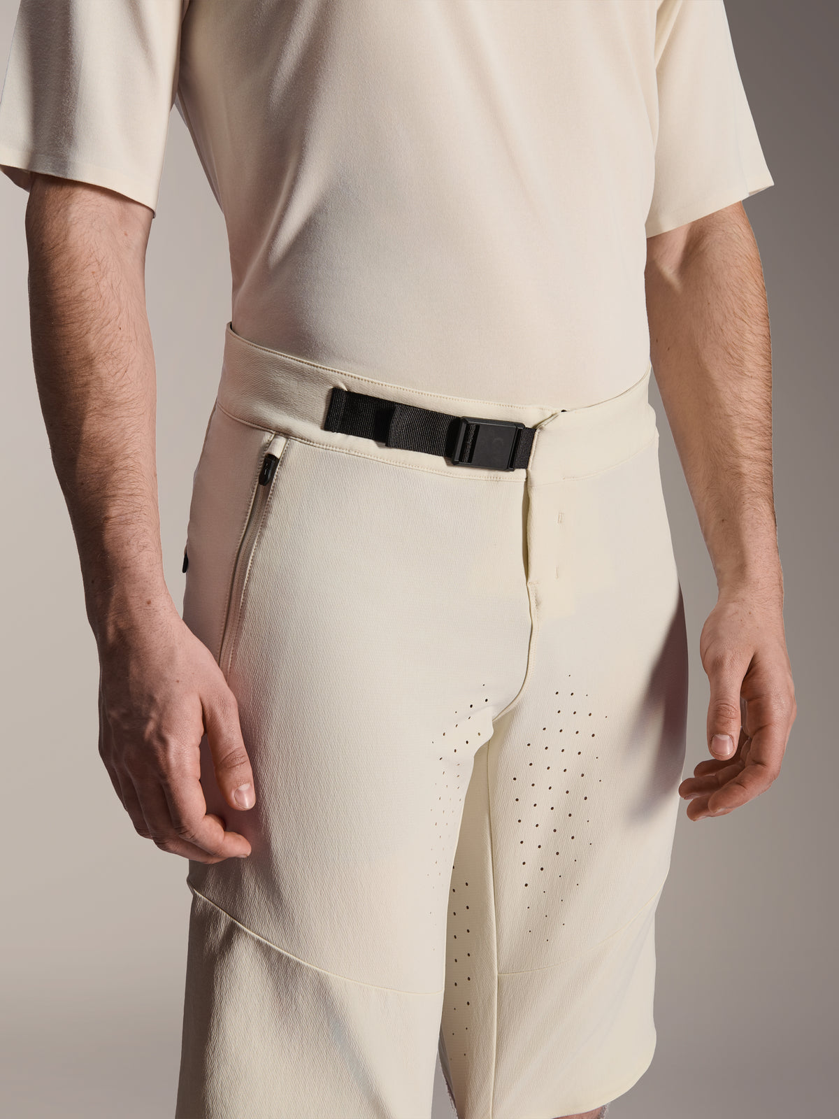 Alpinestars A-Aria Elite Shorts, spodenki rowerowe MTB, ecru, zbliżenie na czarną magnetyczną klamrę, boczną kieszeń na zamek i laserowo wycinaną wentylację, techniczna odzież rowerowa