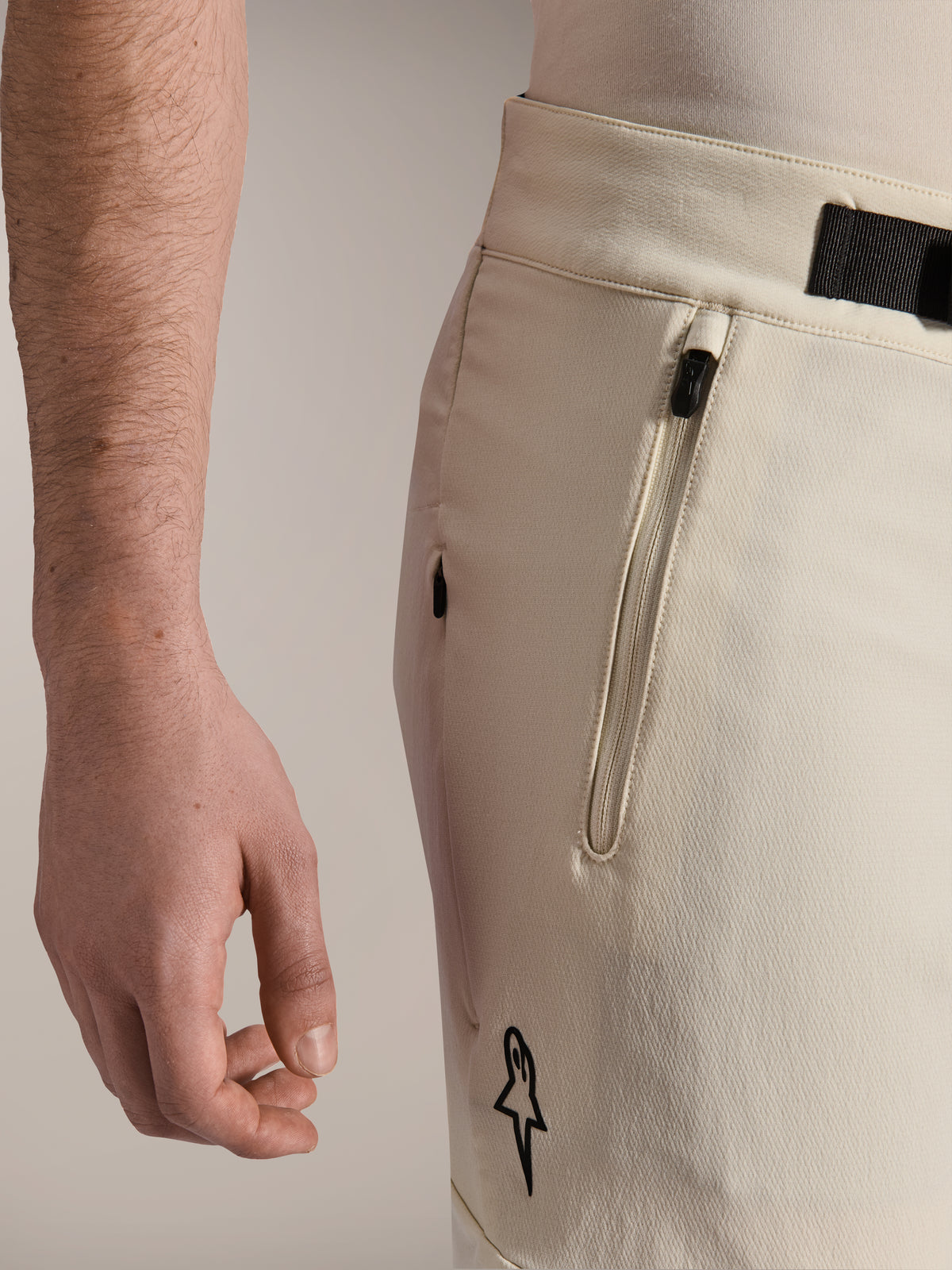 Alpinestars A-Aria Elite Shorts, spodenki rowerowe MTB, ecru, zbliżenie z boku pokazujące kieszeń na zamek i magnetyczne zapięcie na klamrę, odzież kolarska z czarnymi akcentami