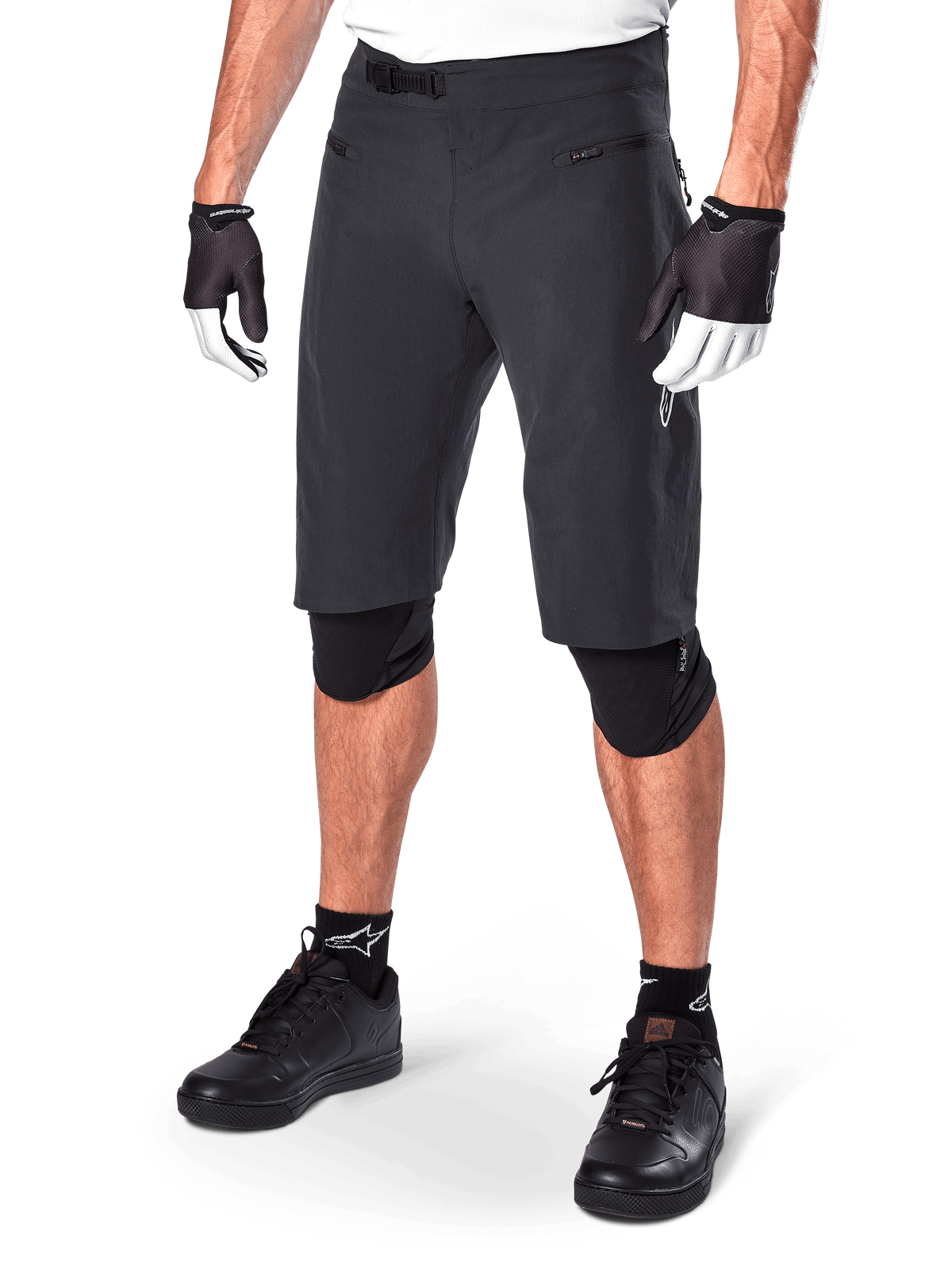 Alpinestars A-Aria Shorts, spodenki do kolarstwa górskiego, czarne, o długości do kolan, z przednimi kieszeniami na zamek i regulowaną klamrą zapadkową w pasie, noszone z czarnymi ochraniaczami na kolana, skarpetami i rękawiczkami rowerowymi