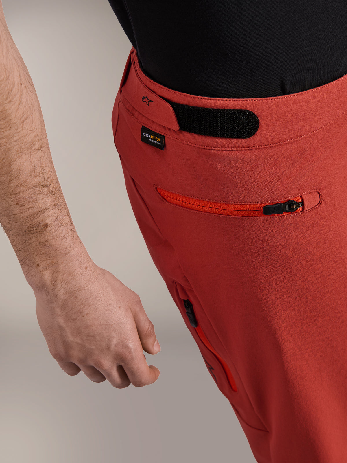 Alpinestars A-Dura Elite Shorts, ciemnopomarańczowe, zbliżenie na profil boczny z regulacją pasa na rzep, logo Cordura® i zapinaną na zamek kieszenią boczną, spodenki rowerowe MTB premium