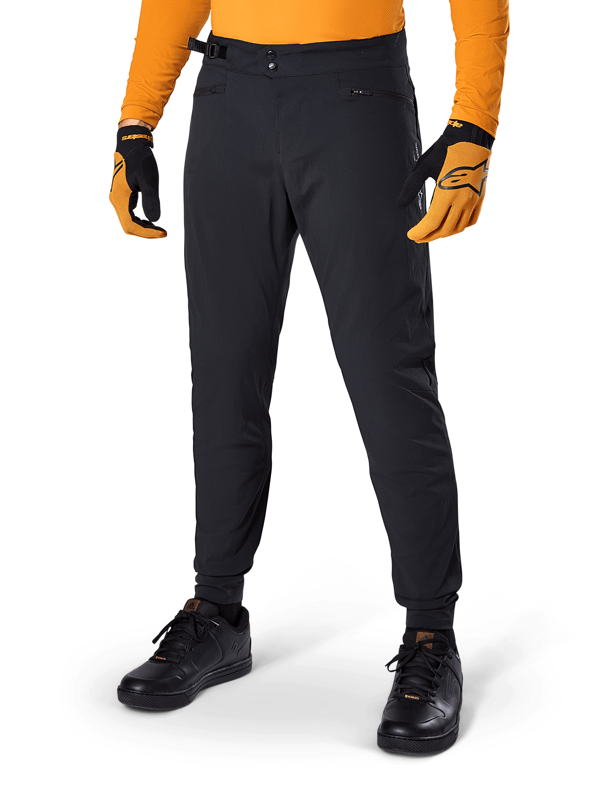 Alpinestars A-Dura Pants, spodnie rowerowe MTB, czarne, boczne paski regulacyjne w pasie i kieszenie na zamek, noszone z pomarańczową koszulką i rękawiczkami, sportowy krój regularny do jazdy MTB