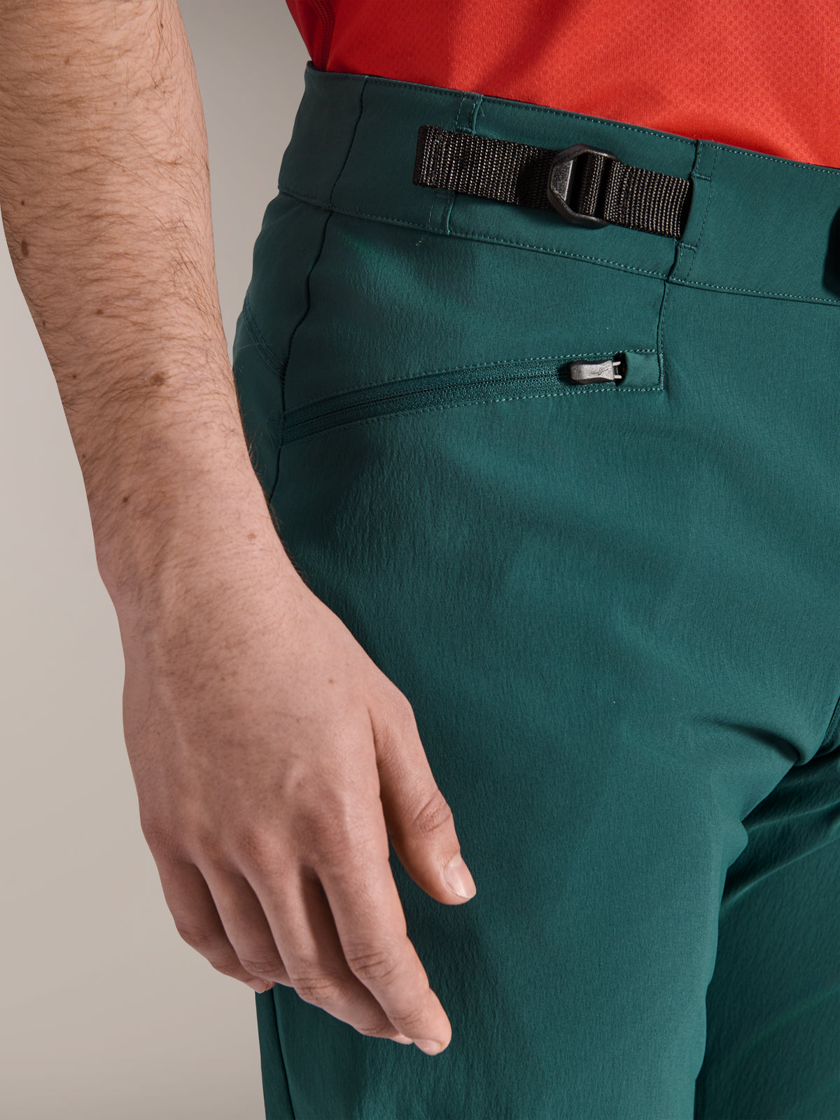 Zbliżenie na spodnie Alpinestars A-Dura w kolorze Dark Pine green, z regulowanym bocznym zapięciem i kieszenią zapinaną na zamek z wyściółką z siatki, wytrzymała odzież na rower górski do jazdy w terenie.