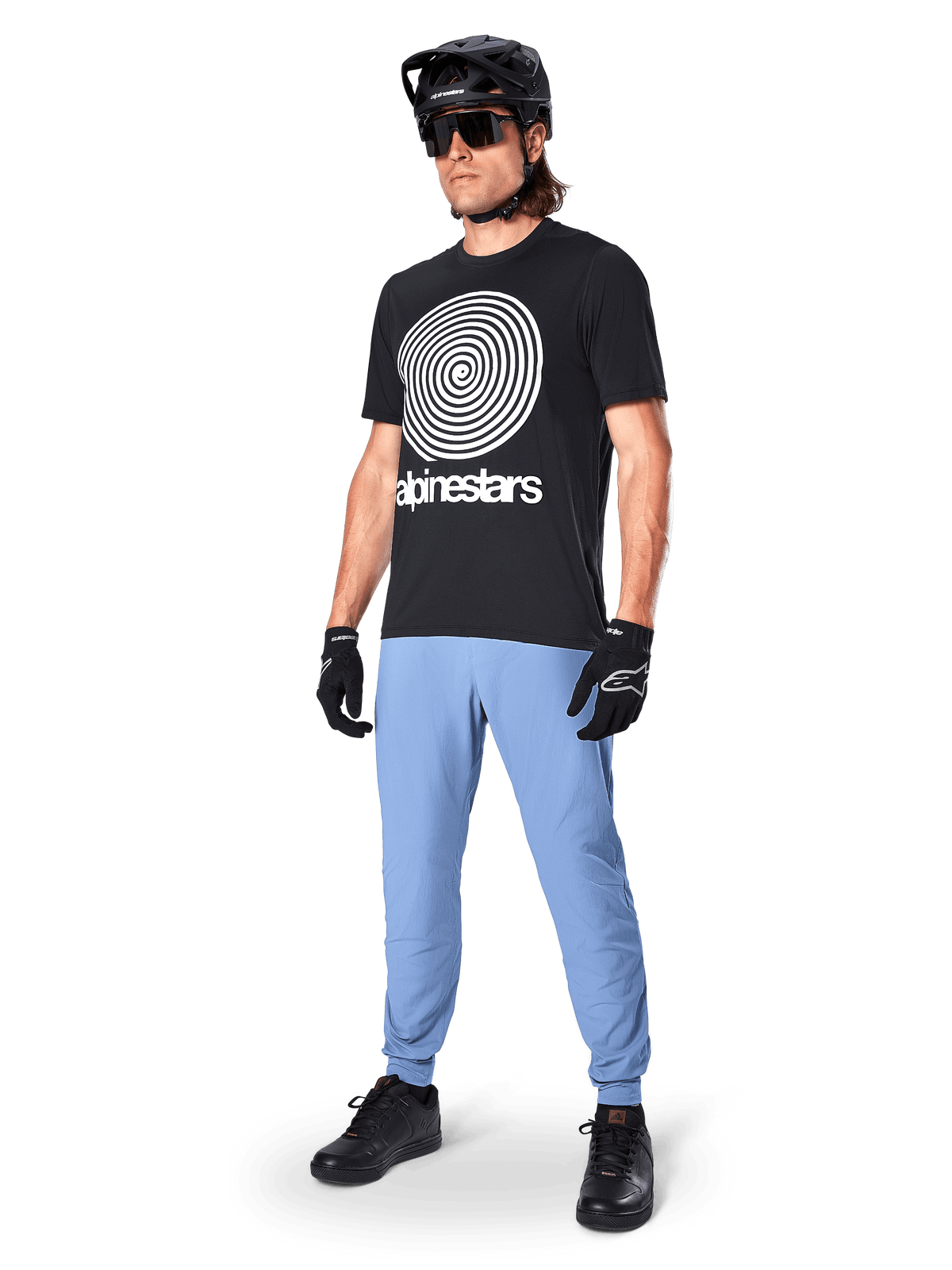 Spodnie Alpinestars A-Dura, spodnie MTB, Infinity Blue, noszone z czarnym t-shirtem z białym spiralnym logo, czarnym kaskiem, okularami przeciwsłonecznymi i czarnymi rękawiczkami, profesjonalny sprzęt do kolarstwa górskiego