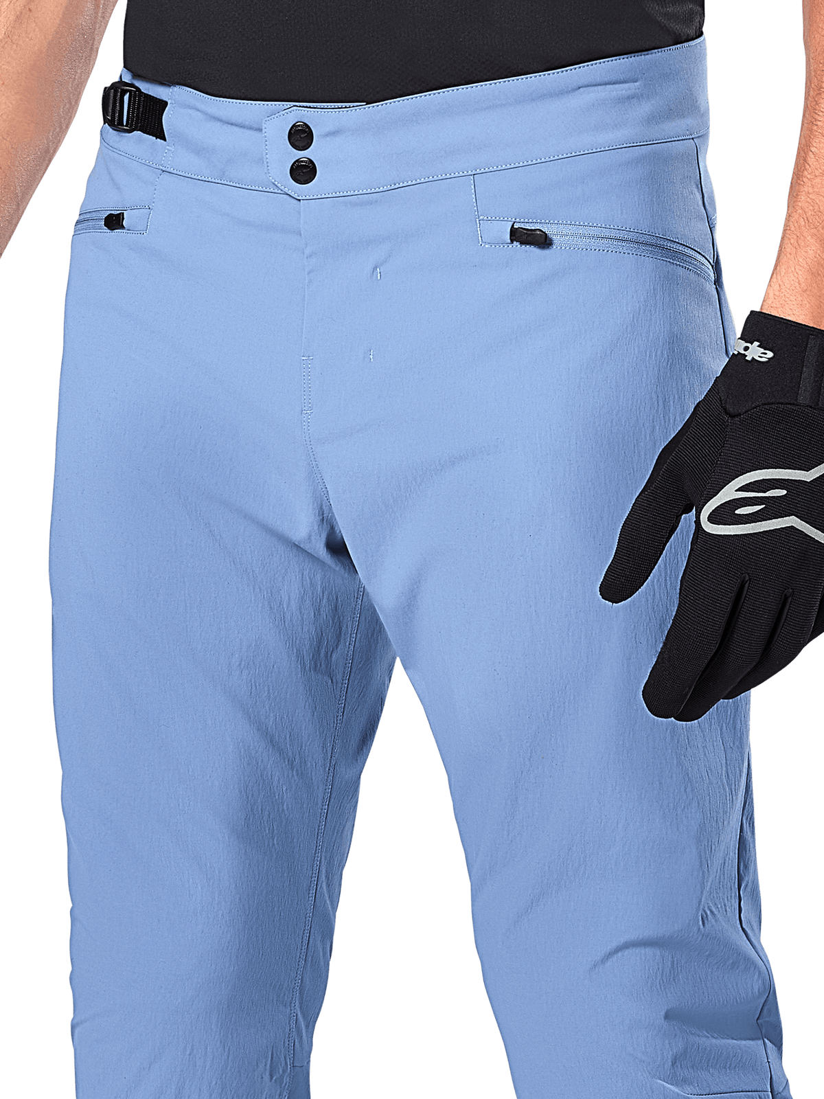 Alpinestars A-Dura Pants, spodnie rowerowe MTB, kolor Infinity Blue, zbliżenie na talię z podwójnym zapięciem na zatrzaski i bocznym regulatorem, kieszenie na zamek, noszone z czarnymi rękawicami Alpinestars