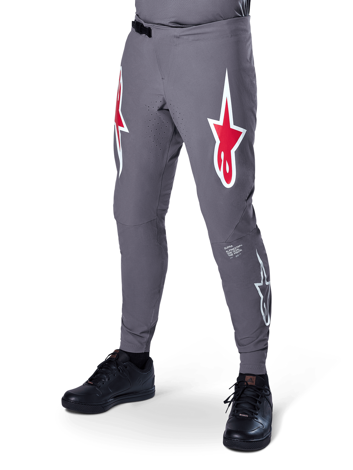 Alpinestars A-Supra Race Pants, ciemnoszare spodnie rowerowe MTB, z dużymi czerwono-białymi logotypami gwiazdy na udach, laserową perforacją dla wentylacji i zapięciem na zapadkę, sportowy krój do downhillu i enduro