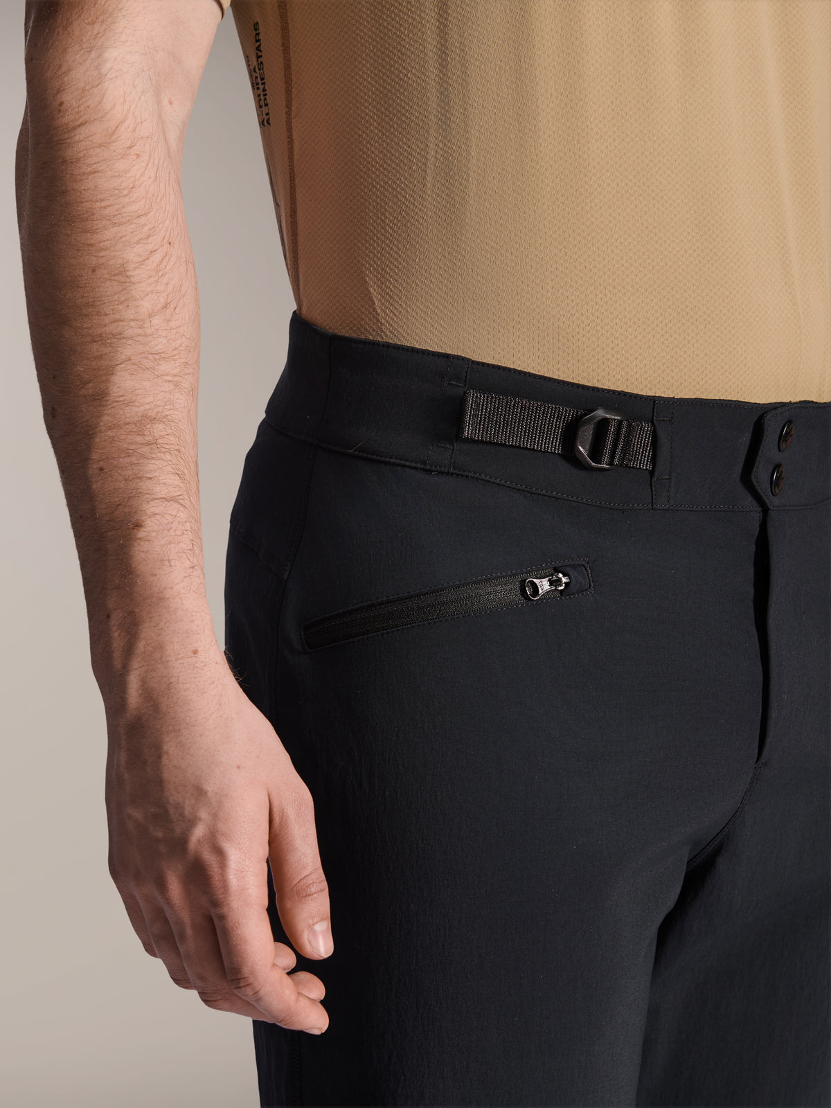 Alpinestars A-Dura Shorts, czarne spodenki MTB, zbliżenie na kieszeń zapinaną na zamek i regulowany boczny ściągacz, podwójne zapięcie na napy, wytrzymały materiał do kolarstwa górskiego