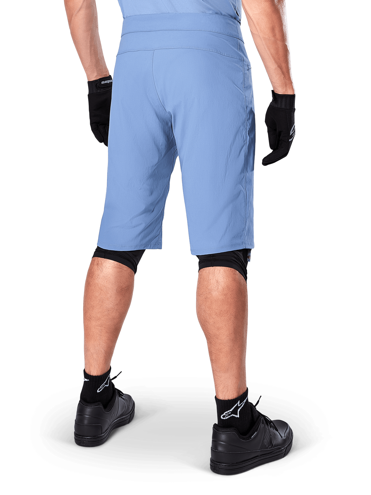 Alpinestars A-Dura Shorts, spodenki MTB w kolorze Infinity Blue, widok z tyłu, zestawione z czarnymi rękawiczkami, nakolannikami i czarnymi skarpetkami z białym logo gwiazdy, wytrzymały, rozciągliwy materiał do jazdy w terenie
