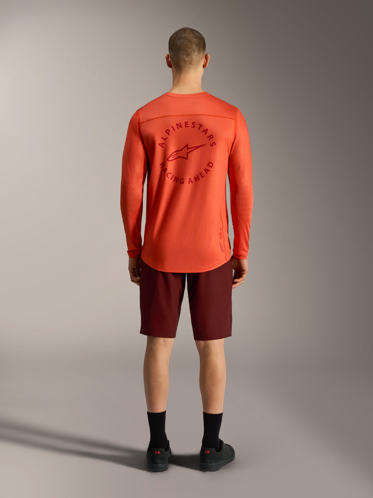 Alpinestars orange long-sleeve MTB jersey and Bordeaux A-Dura Ride Shorts, rear view of technical cycling apparel.