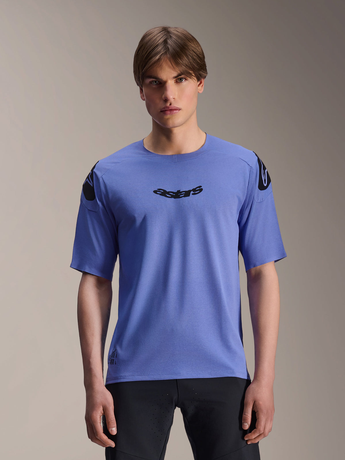 Alpinestars A-Aria Polartec Elite Jersey, koszulka MTB z krótkim rękawem, niebieska (Baja Blue), noszona przez modela, z czarnym napisem „astars” na klatce piersiowej i logo na ramionach, profesjonalna odzież do jazdy po szlakach.