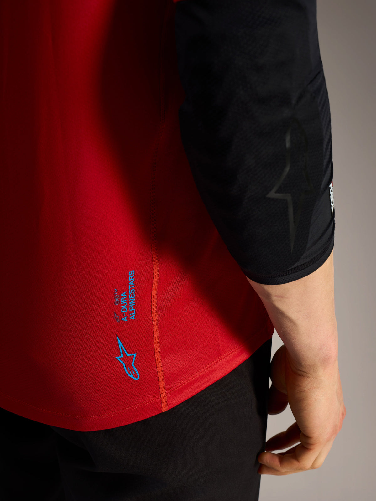 Czerwona koszulka A-Dura Ride MTB, niebieskie logo Alpinestars i techniczny materiał o wysokiej wydajności.