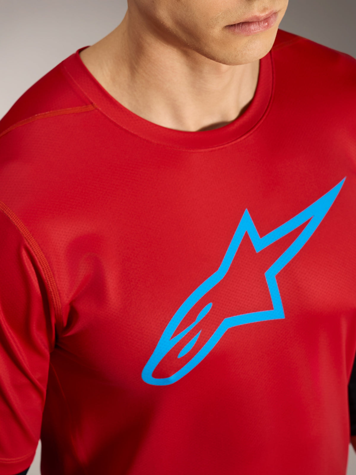 Czerwona koszulka Alpinestars A-Dura Ride SS z błękitnym logo, techniczna odzież na rower górski.