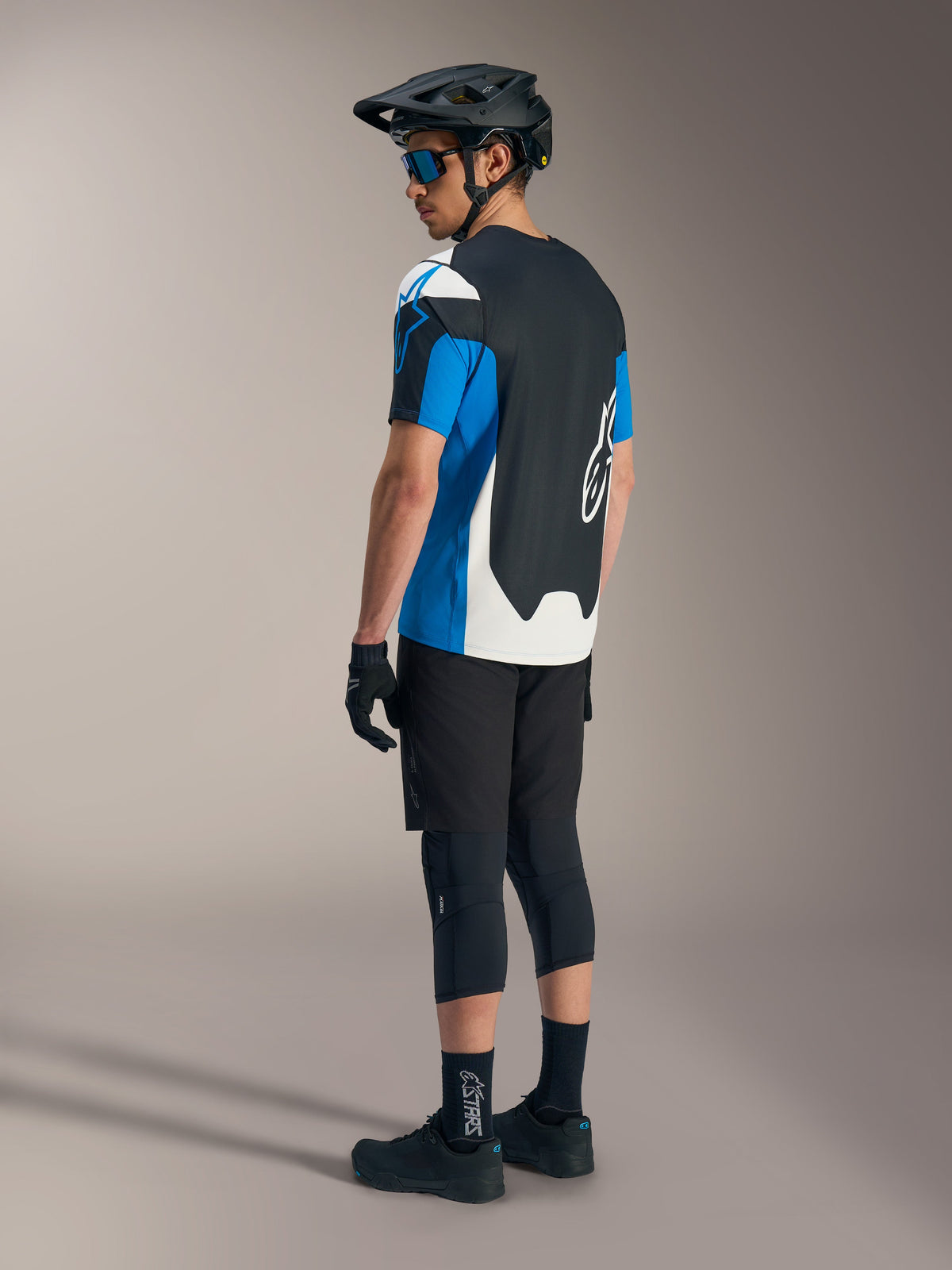 Alpinestars A-Dura Race SS Jersey in blue and black with black MTB shorts, helmet, and protective mountain bike gear.