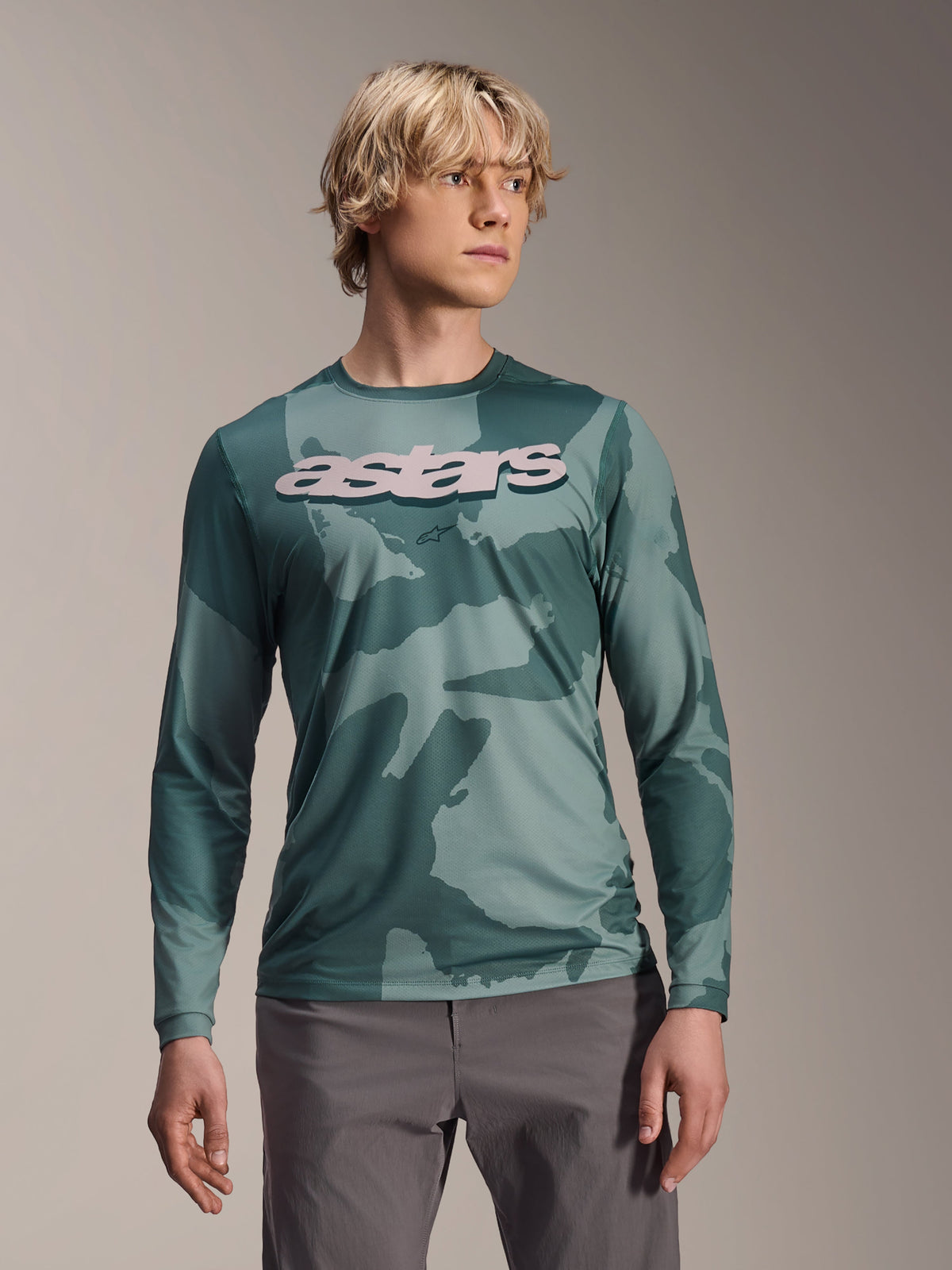 Alpinestars A-Dura Hollow Camo Long Sleeve Jersey, koszulka MTB z długim rękawem, zielony wzór moro Silver Pine Camo, duże jasnoszare logo astars na piersi, zestawiona z szarymi spodniami, profesjonalna odzież do kolarstwa górskiego