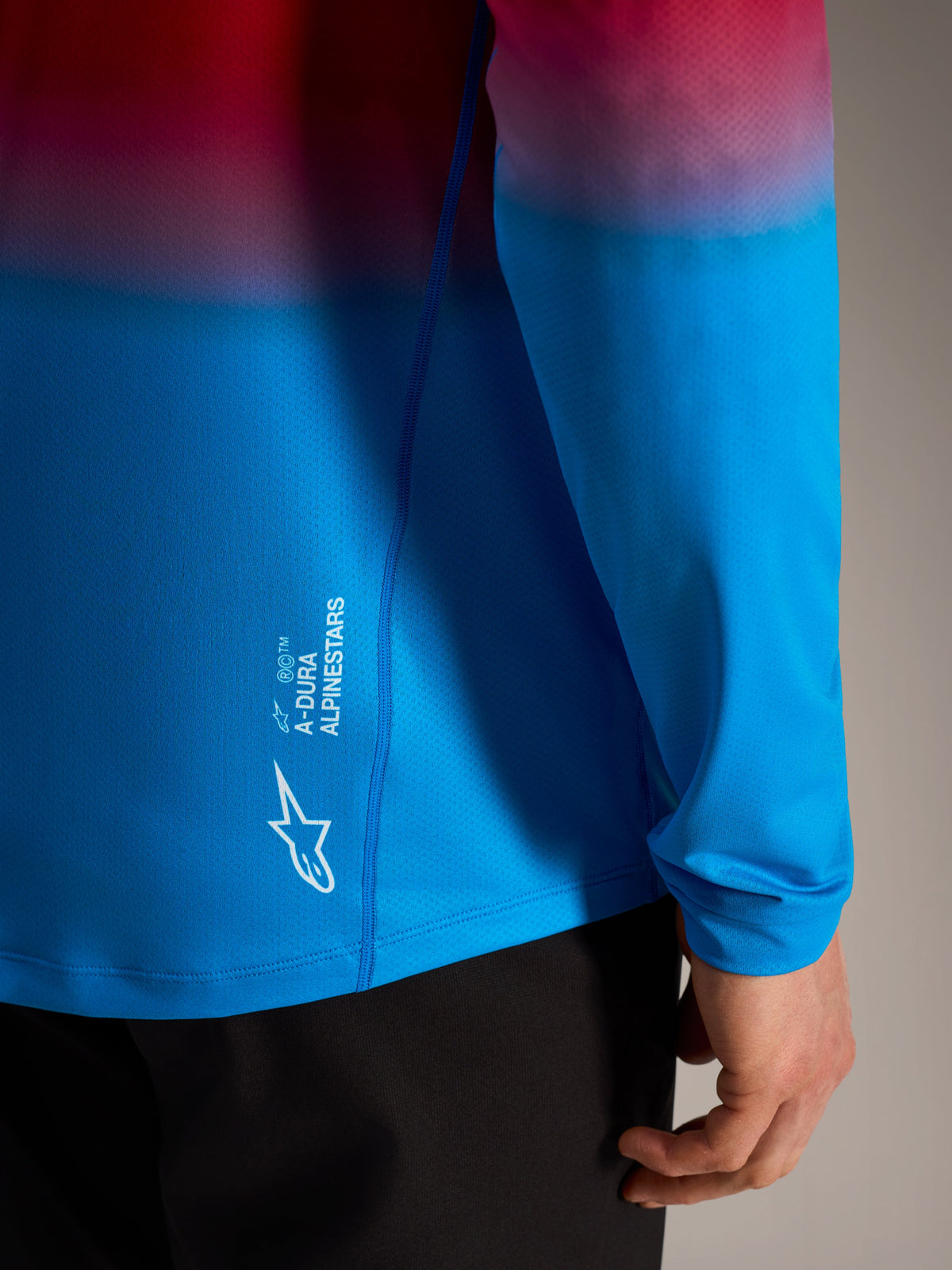 Koszulka A-Dura ASTARS 2.0 z długim rękawem, czerwono-niebieski gradient i białe logo Alpinestars na boku.