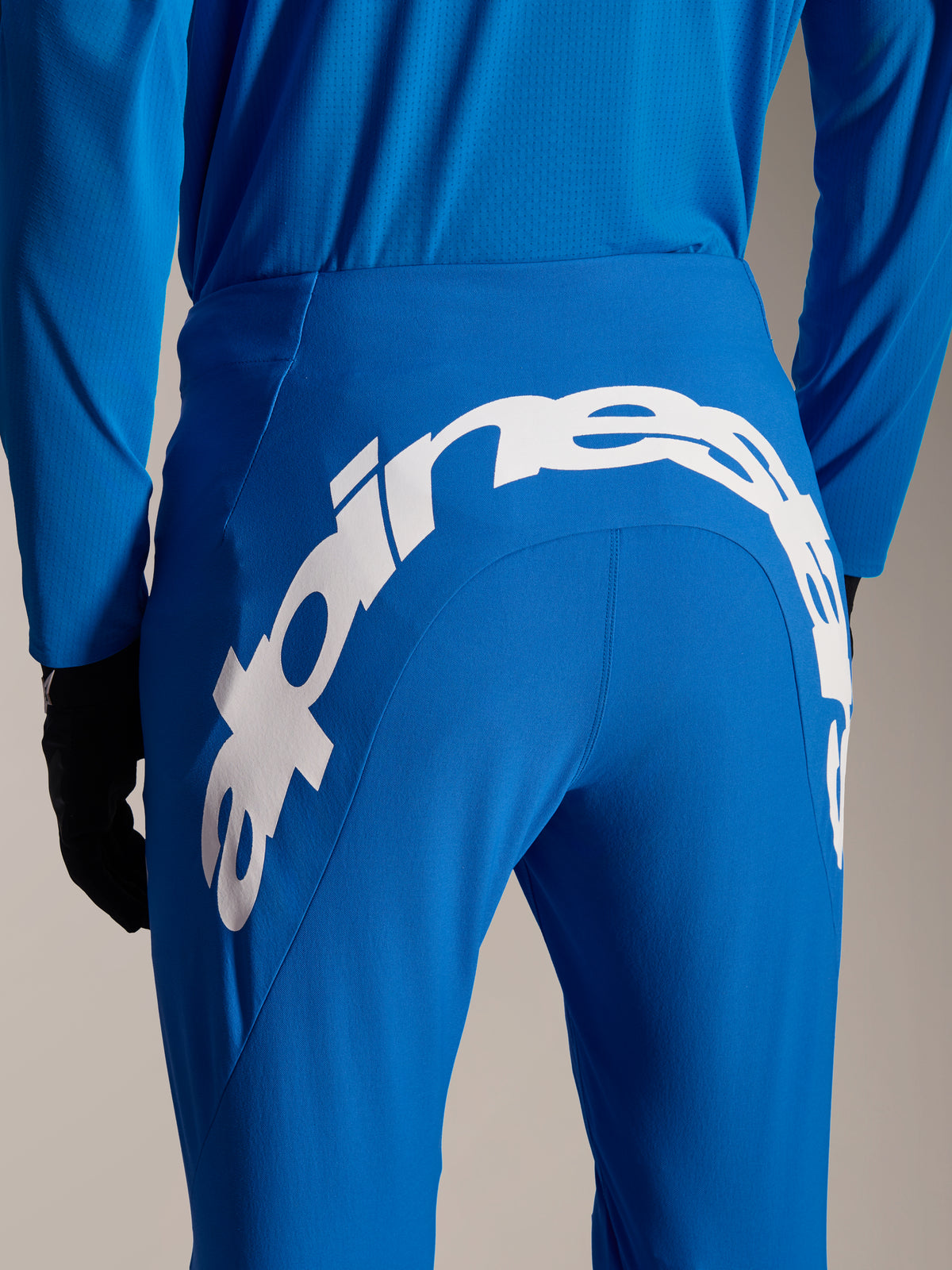 Alpinestars A-Supra Melt Pants and Jersey, Blue MTB gear, rear view featuring large white Alpinestars wordmark on the back yoke of the pants, matching long-sleeve jersey and black gloves