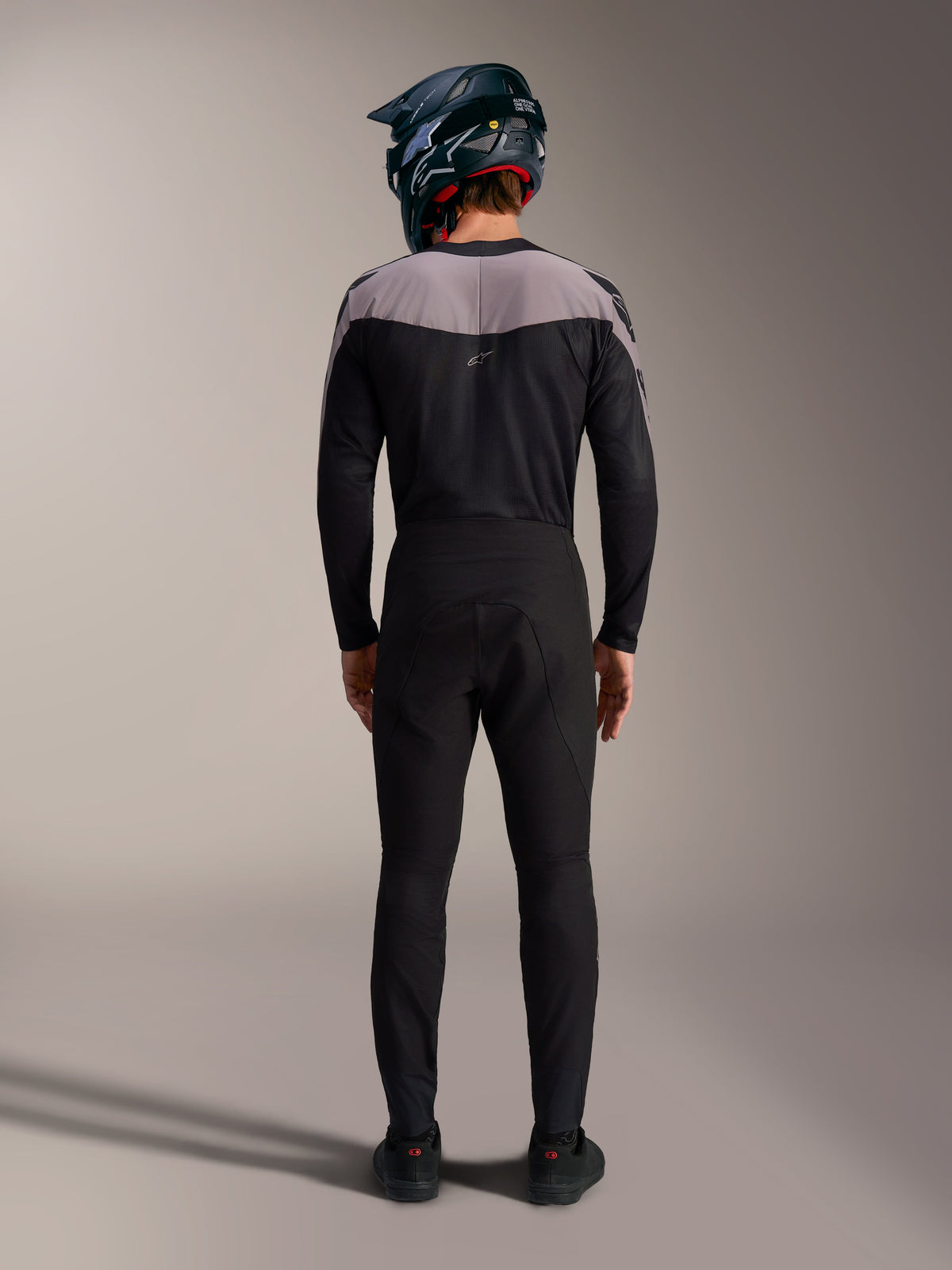 Czarny zestaw MTB Alpinestars A-Supra Elite, techniczne spodnie i bluza z kaskiem full-face, widok z tyłu.