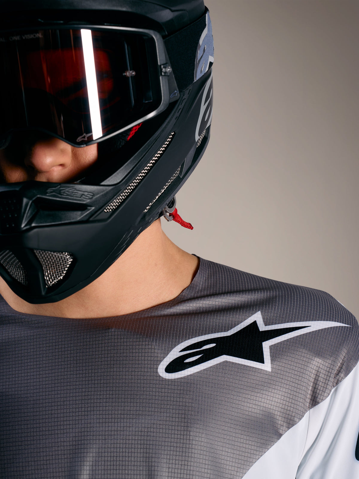 Koszulka Alpinestars A-Supra Elite Faded Gray, mikroperforowana tkanina, białe logo i czarny kask MTB.