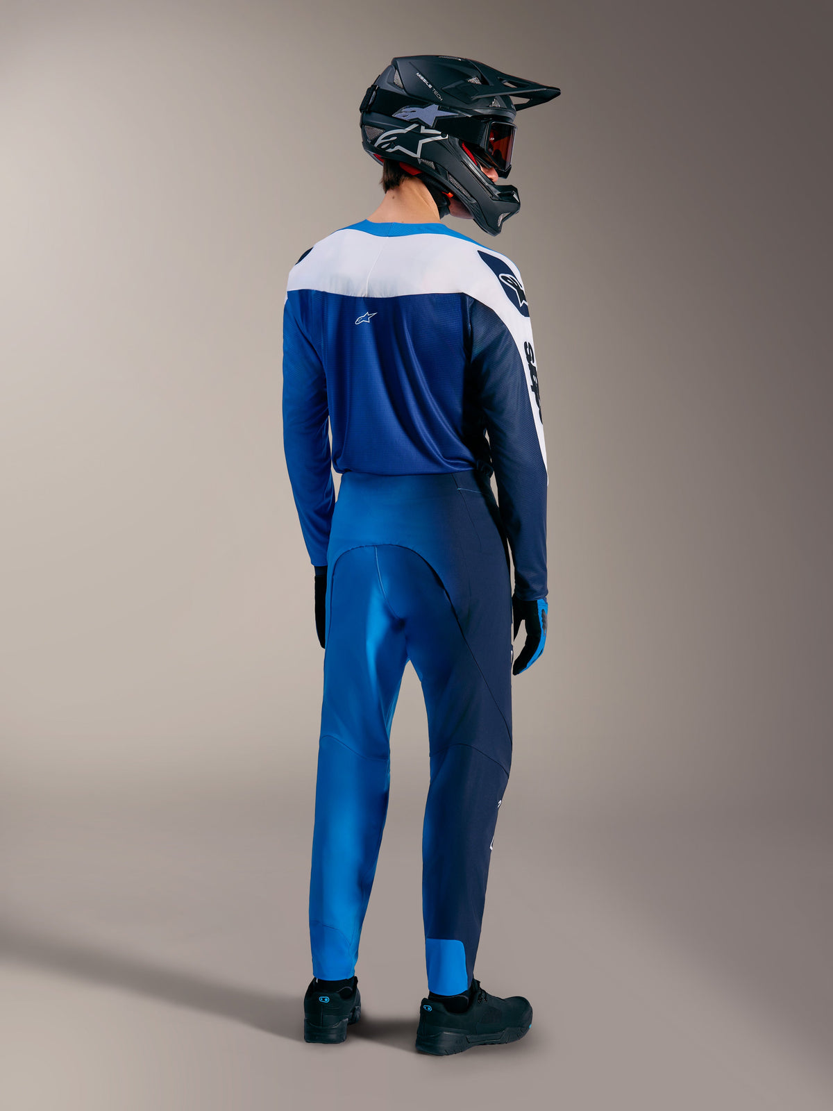 Strój MTB Alpinestars A-Supra Elite Faded Bright Blue, koszulka i spodnie widoczne z tyłu, kask full-face.