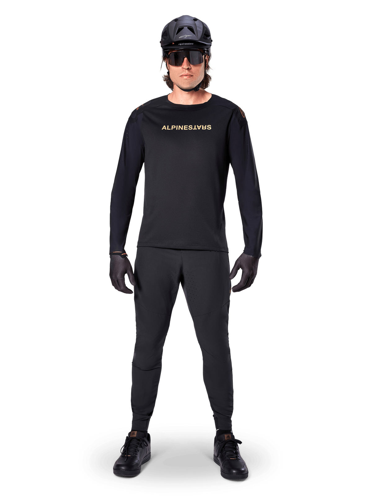 Alpinestars A-Aria Polartec Switch Long Sleeve Jersey, czarna, prezentowana przez kolarza w komplecie z czarnymi spodniami technicznymi, czarnym kaskiem, okularami przeciwsłonecznymi i czarnymi rękawicami, profesjonalny strój MTB na terenowe szlaki