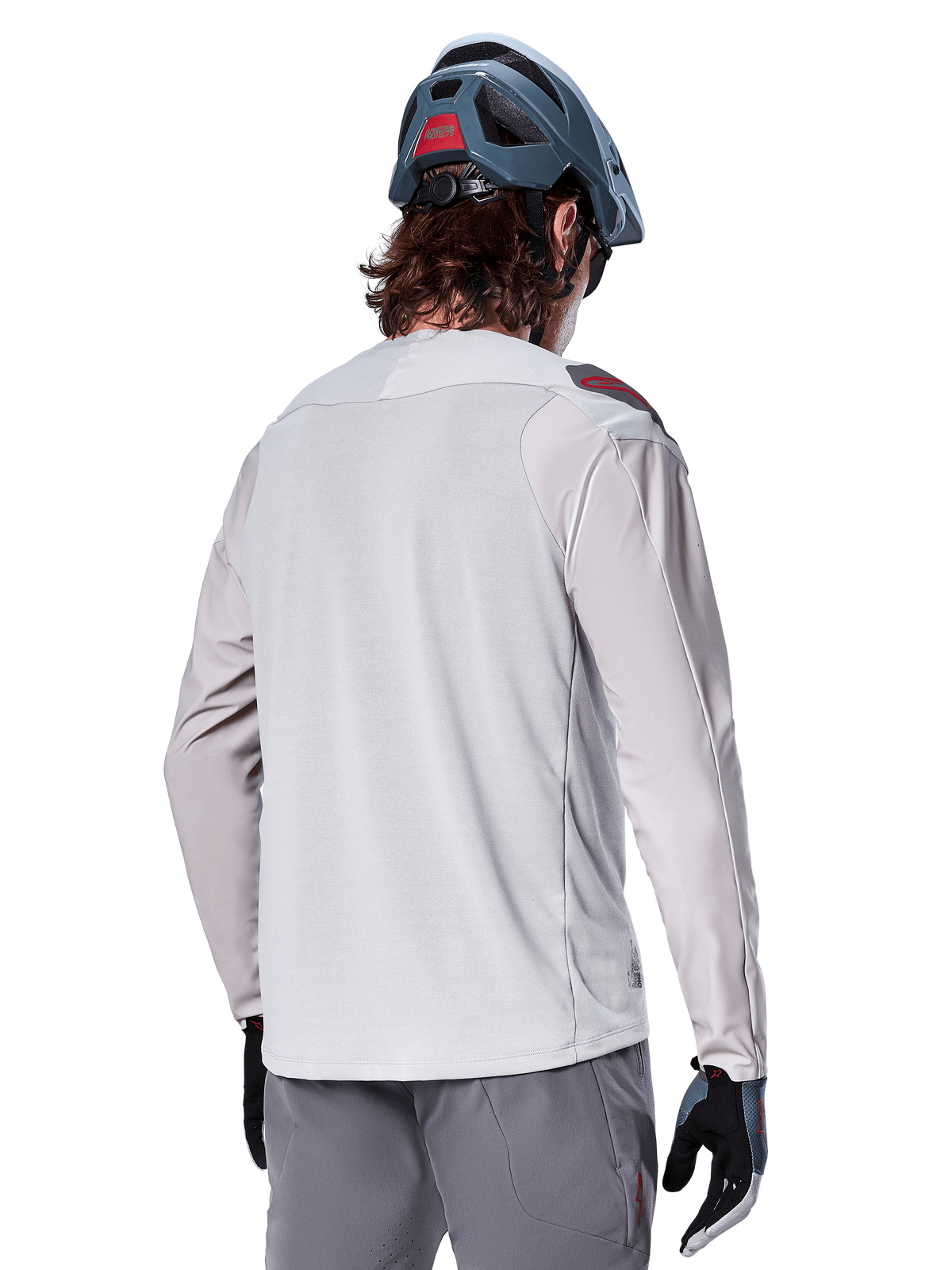 Alpinestars A-Aria Polartec Switch Long Sleeve Jersey, jasnoszara, widok z tyłu na rowerzyście, w zestawieniu z niebieskim kaskiem MTB i szarymi spodniami, techniczna odzież do kolarstwa górskiego na szlaki terenowe