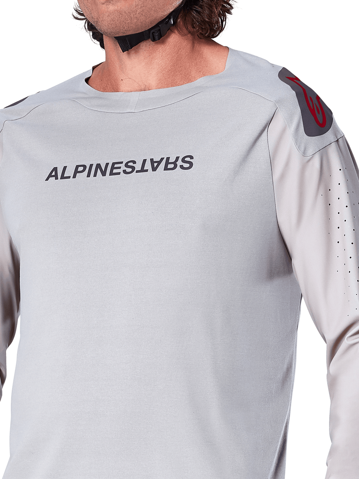 Zbliżenie na jasnoszarą koszulkę z długim rękawem Alpinestars A-Aria Polartec Switch, logo Alpinestars na piersi, czerwone logo na ramieniu i laserowo perforowane rękawy zapewniające przepływ powietrza, wysokiej jakości odzież MTB