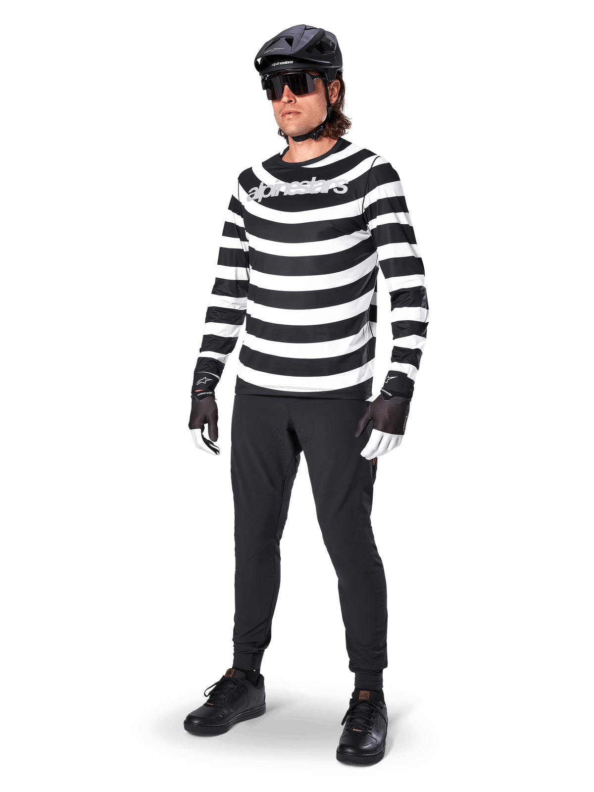 Alpinestars A-Aria Oscar Long Sleeve Jersey, czarno-biała koszulka z długim rękawem w wyraźne poziome, spiralne pasy, białe zakrzywione logo Alpinestars, sportowa odzież MTB noszona z czarnymi spodniami rowerowymi i kaskiem