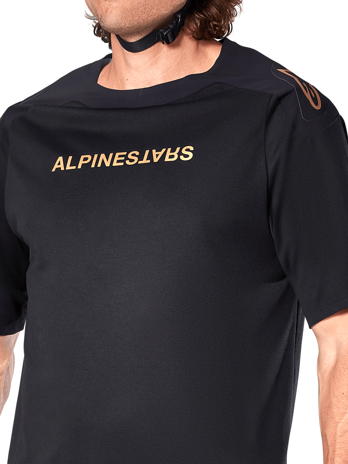 Alpinestars A-Aria Polartec Switch Jersey, koszulka MTB z krótkim rękawem, czarna, złoty napis Alpinestars na klatce piersiowej i logo na ramieniu, zbliżenie na górną część tułowia podkreślające techniczny materiał i sportowy krój