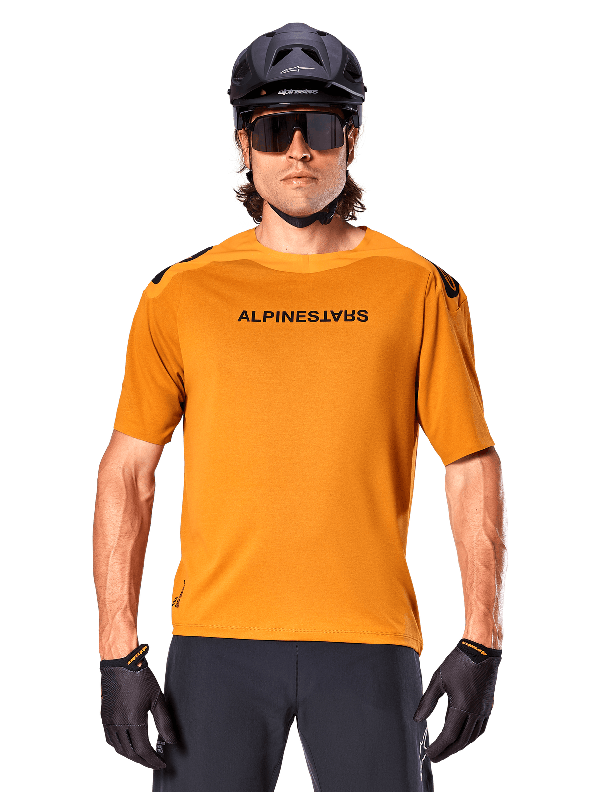 Koszulka Alpinestars A-Aria Polartec Switch z krótkim rękawem, ciemnozłota, rowerzysta górski w czarnym kasku i okularach przeciwsłonecznych, wyczynowa odzież rowerowa na szlaki MTB