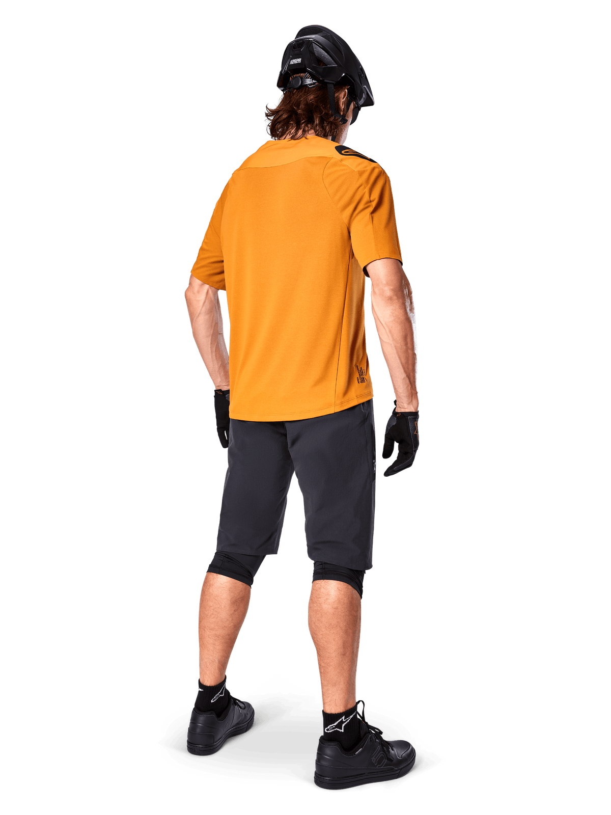 Koszulka Alpinestars A-Aria Polartec Switch, koszulka MTB z krótkim rękawem, kolor Dark Gold, widok z tyłu na modela ubranego w ciemnoszare spodenki na rower górski, czarny kask i rękawiczki, techniczna odzież kolarska na szlaki terenowe
