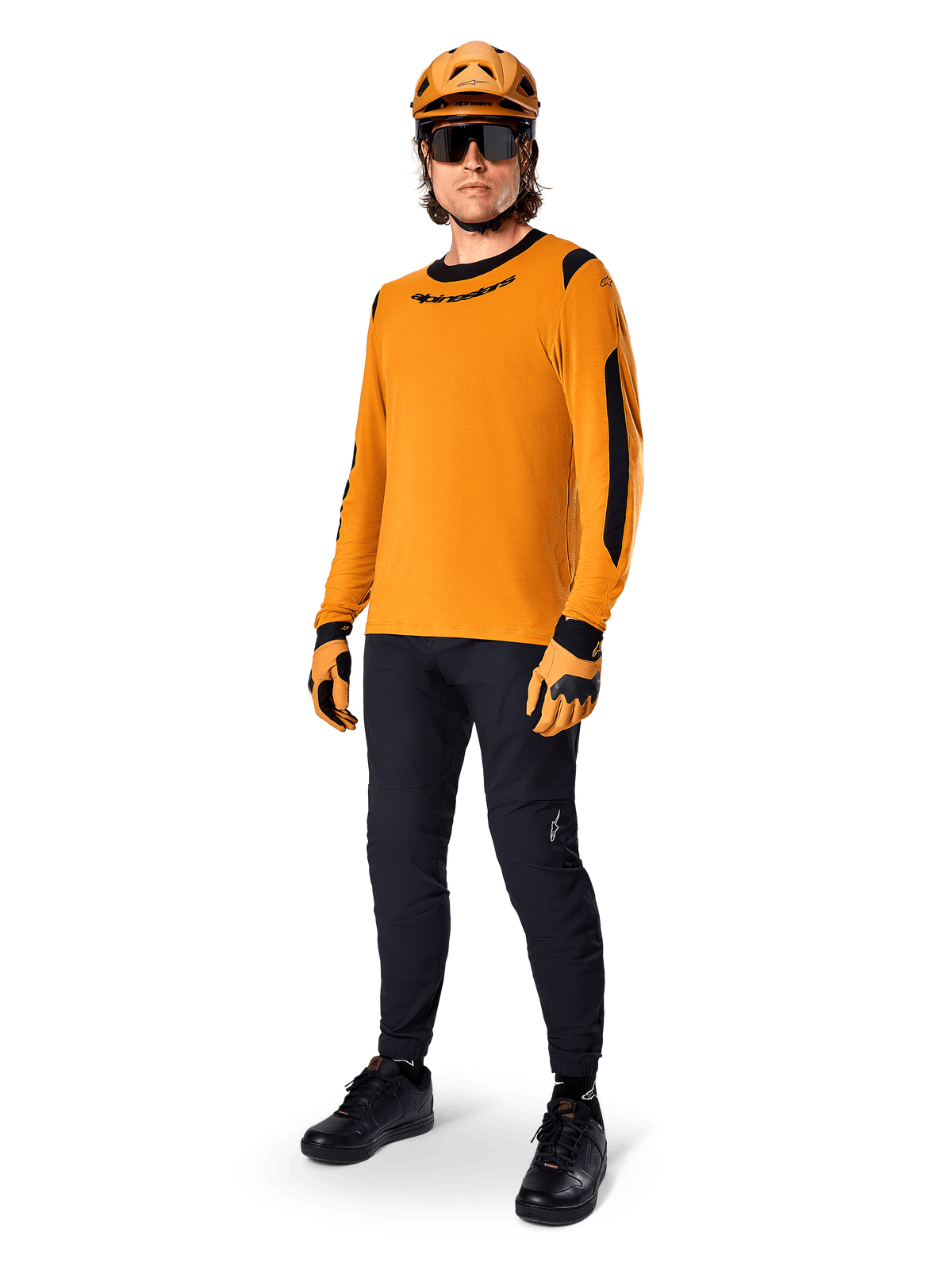 Alpinestars A-Dura Dri Wool Jersey - Long Sleeve, ciemnozłoty, noszony z dopasowanym pomarańczowym kaskiem, czarnymi spodniami MTB i żółto-czarnymi rękawicami, pełny strój rowerowy do jazdy terenowej