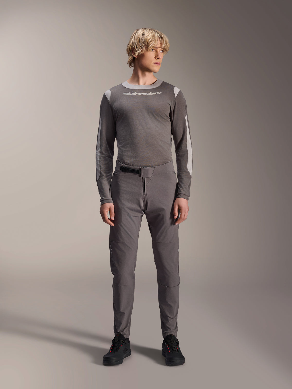Alpinestars A-Dura Elite Pants, Dark Gray mountain bike pants, full-body view, worn with a coordinating gray long-sleeve performance jersey featuring the Alpinestars logo, black shoes with red accents, athletic cycling outfit