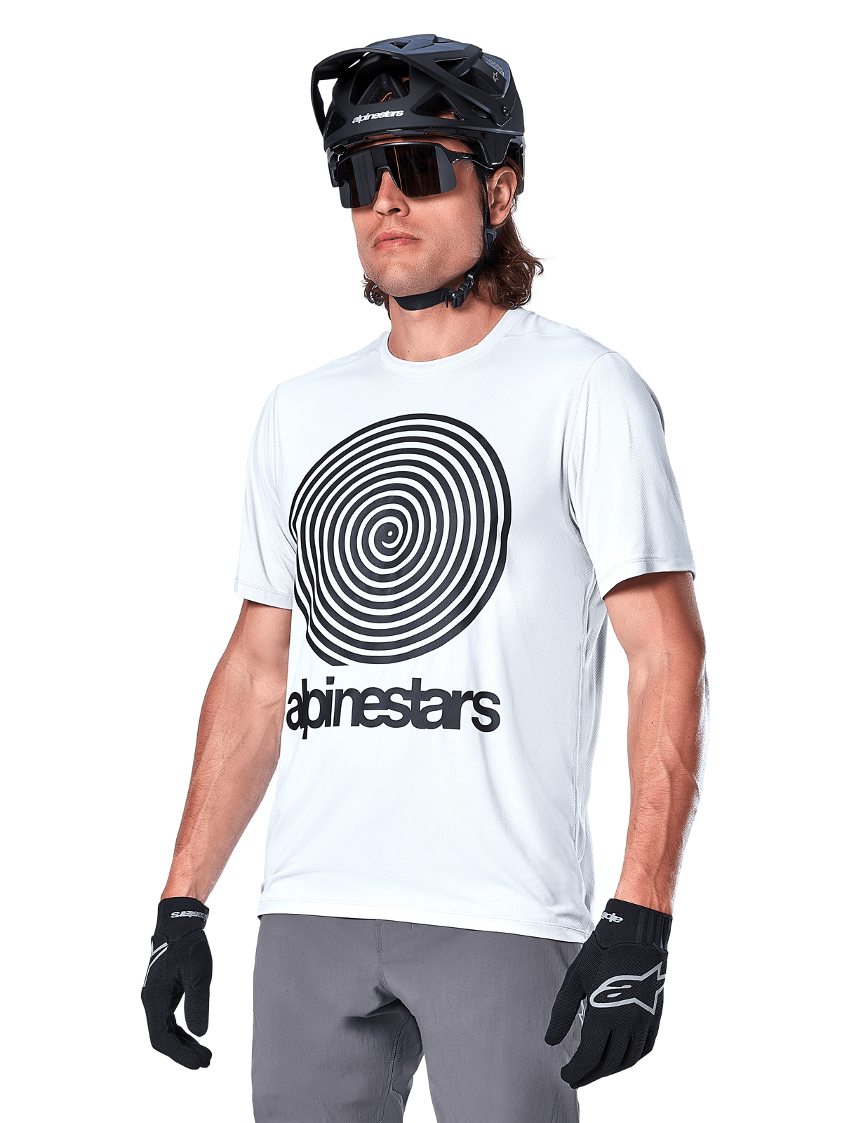 Koszulka Alpinestars A-Dura Oscar z krótkim rękawem, biała z czarną spiralną grafiką heritage i logo, noszona z czarnym kaskiem MTB i rękawiczkami, sportowa odzież do kolarstwa górskiego