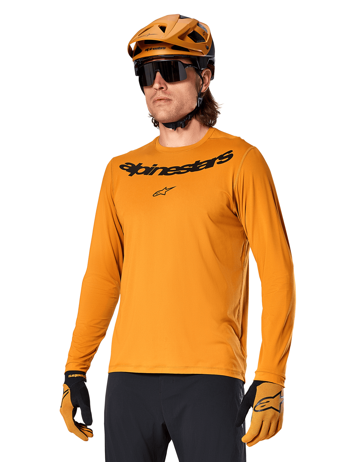 Alpinestars A-Dura Rocker Long Sleeve Jersey, koszulka rowerowa MTB, kolor ciemnozłoty, osoba w koszulce z dopasowanym kaskiem i rękawiczkami, sportowy spójny zestaw z napisem Alpinestars na piersi