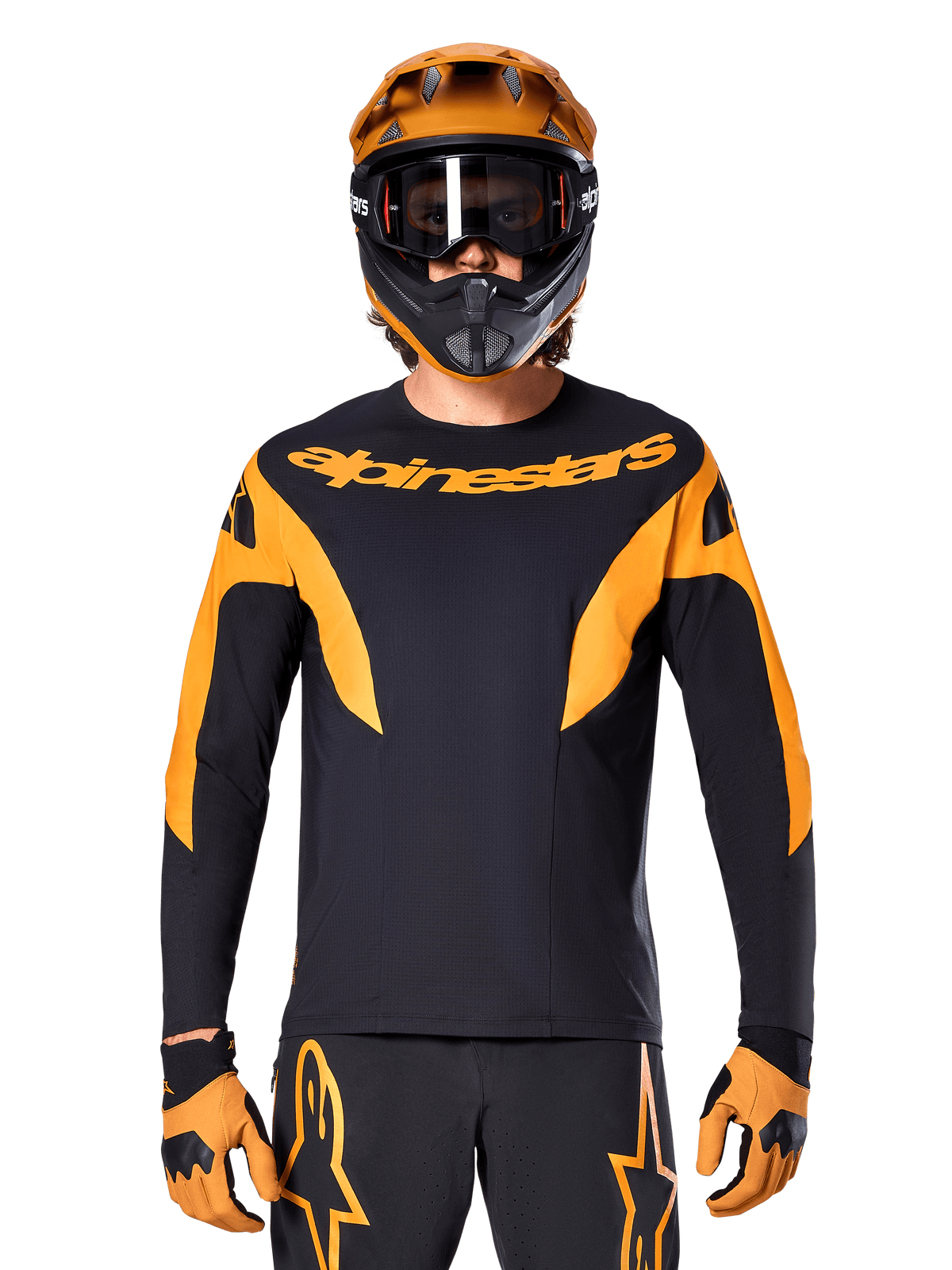 Rowerzysta MTB w koszulce Alpinestars A-Supra Race z długim rękawem, czarna z pomarańczową grafiką i logo na piersi, w zestawie z pomarańczowym kaskiem full-face, czarnymi goglami i pomarańczowymi rękawicami, profesjonalny strój do wyścigów górskich