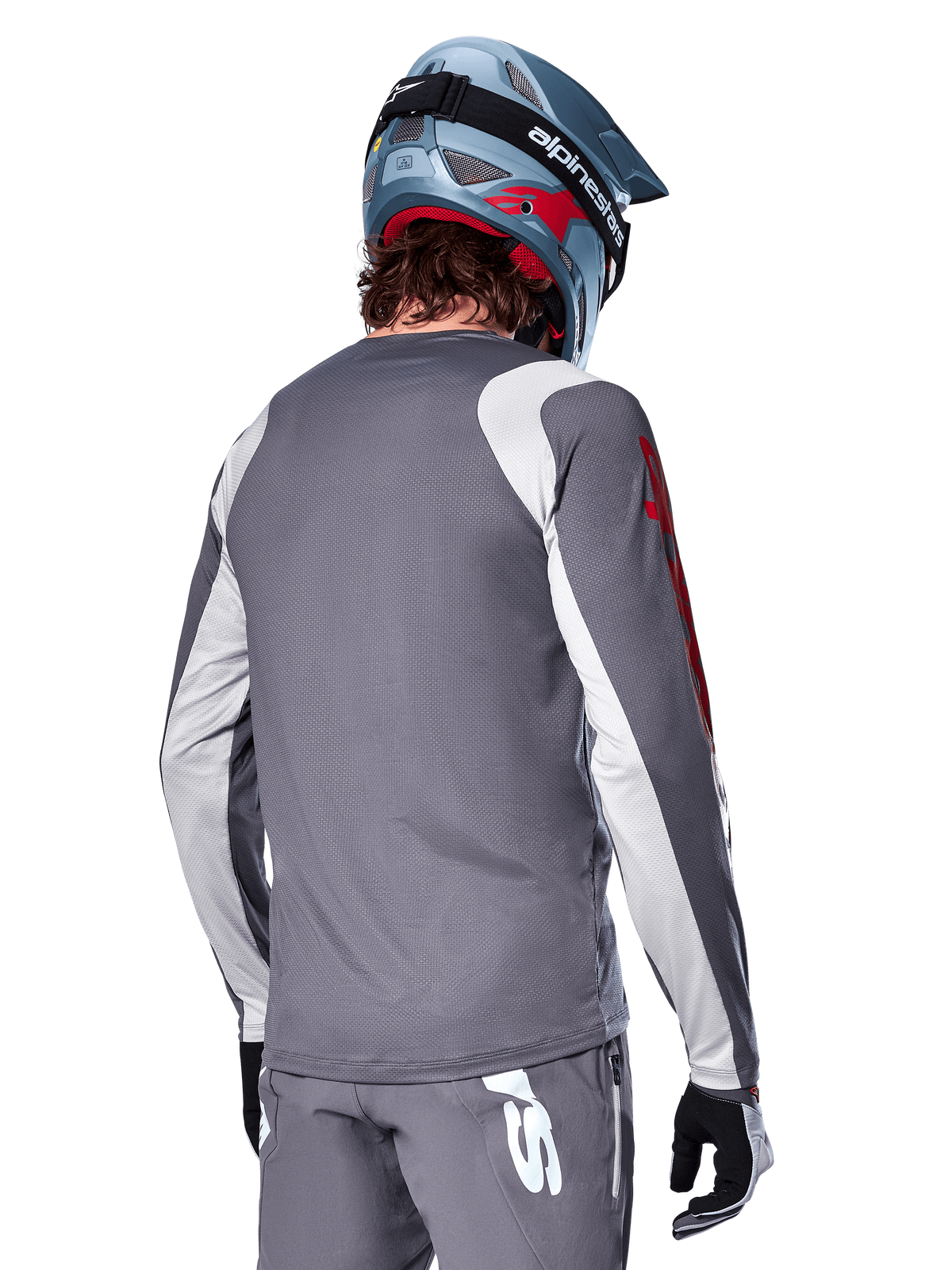 Koszulka Alpinestars A-Supra Astar z długim rękawem, ciemnoszara z jasnoszarymi panelami na ramionach i rękawach, widok z tyłu na rowerzystę w niebieskim kasku full-face i szarych spodniach, sportowa odzież rowerowa MTB