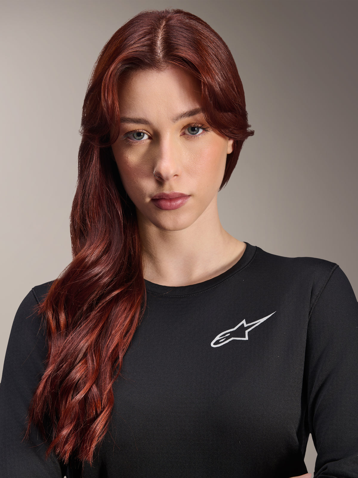 Alpinestars Stella A-Dura Thermal Jersey, damska koszulka MTB z długim rękawem, czarna z białym logo A-star na piersi, zbliżenie na portret kobiety z długimi rudymi włosami, odzież rowerowa na chłodne dni
