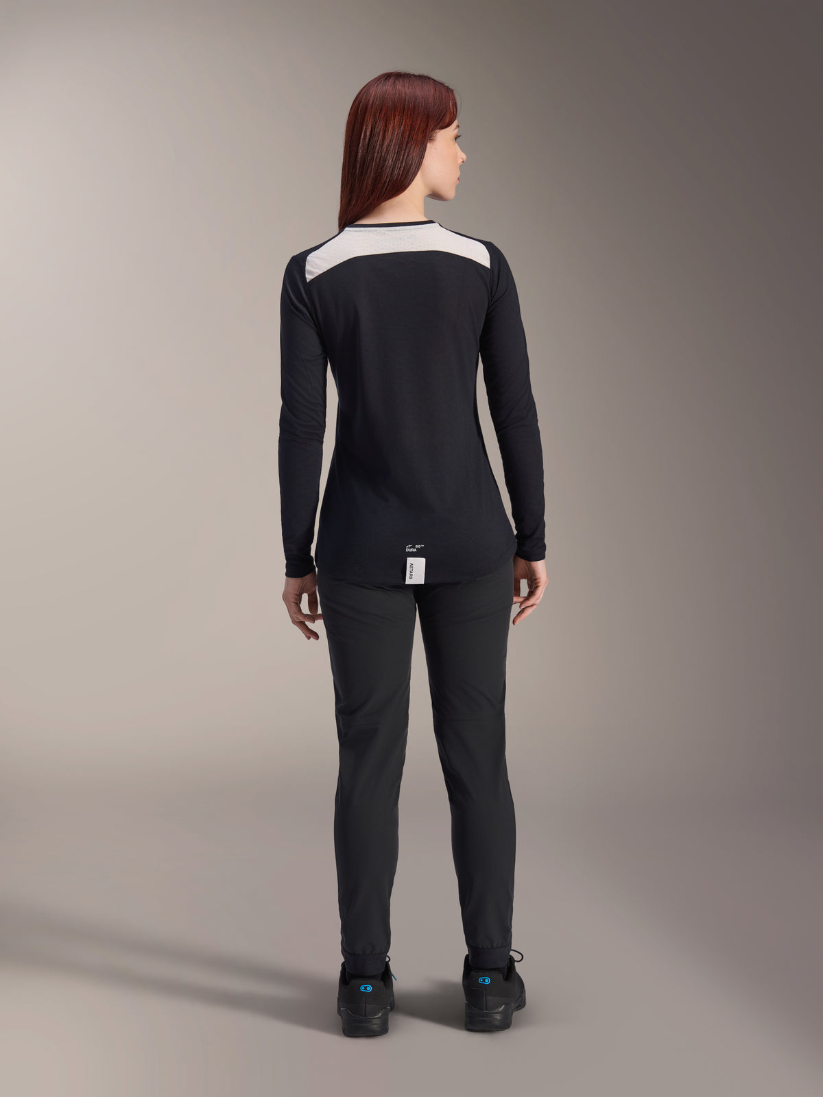 Alpinestars Stella A-Dura Dri Astar Long Sleeve Jersey, damska czarna koszulka MTB, widok z tyłu z białym siatkowym panelem wentylacyjnym na ramionach, w zestawieniu z czarnymi spodniami rowerowymi, techniczna odzież do jazdy terenowej