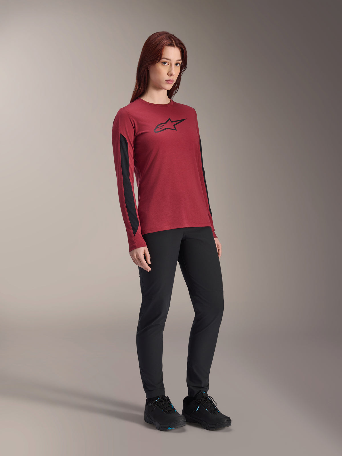 Damska koszulka Alpinestars Stella A-Dura Dri Astar z długim rękawem, bordowa z czarnym logo na piersi i czarnymi panelami z siatki na rękawach, zestawiona z czarnymi spodniami technicznymi i czarnymi butami rowerowymi, wysokowydajna odzież do kolarstwa górskiego dla kobiet