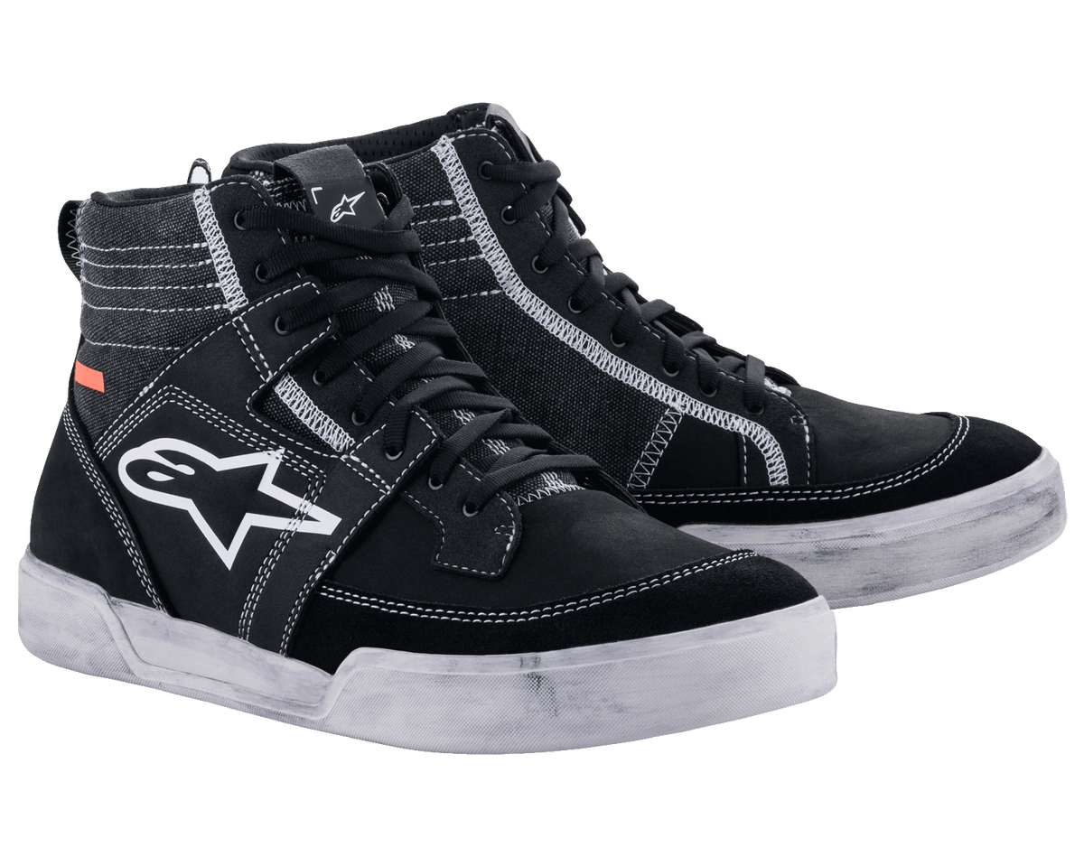 Alpinestars Ageless Riding Shoes, miejskie obuwie motocyklowe, czarne z białymi kontrastowymi szwami i podeszwami, wysoka sylwetka typu sneaker z dużym białym logo gwiazdy z boku, codzienne obuwie ochronne do jazdy szosowej